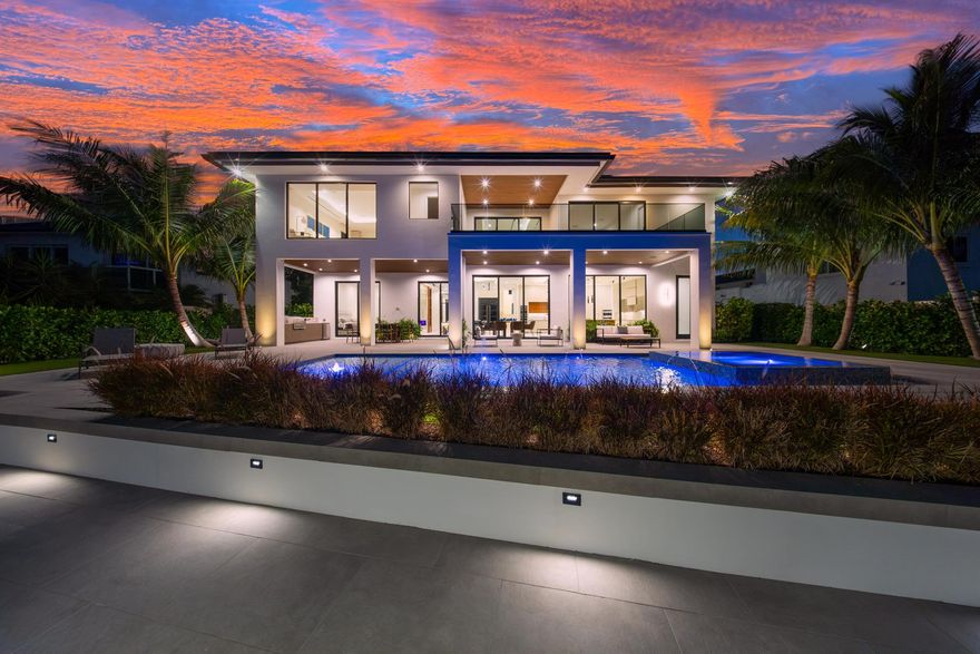 A modern masterpiece, seamlessly blending sleek architectural design, luxurious amenities, and cutting-edge technology to offer an exceptional South Florida lifestyle. Nestled minutes from Hillsboro and Boca Inlets, this waterfront estate provides immediate ocean access, ideal for yachting enthusiasts with its 91-foot yacht dock complete with bumpers, cleats, Shore Power Pedestal, and water supply, all secured by robust concrete pilings and evening lighting. The home's custom architectural design is captivating, combining tropical landscaping with expansive 10-foot PGT impact glass doors that welcome natural light while connecting indoor and outdoor spaces. An entertainer's paradise, the exterior offers a spacious loggia with a summer kitchen,