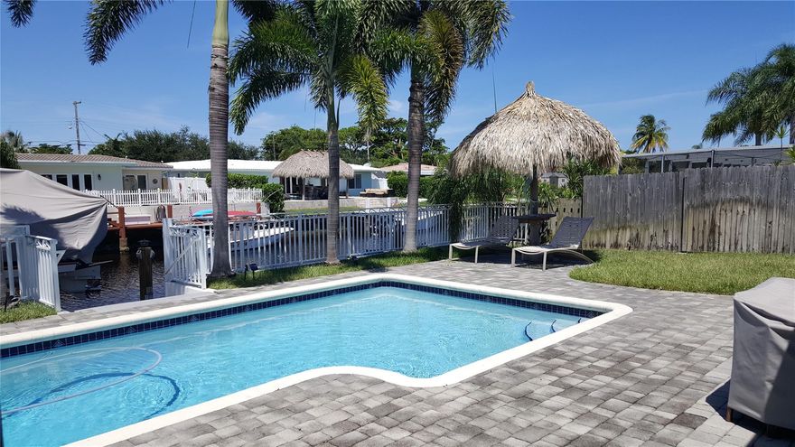 Enjoy direct waterfront living in this beautifully maintained 3-bedroom, 2-bath home with pool, located on a quiet street with excellent access through two fixed bridges. This property features 70 feet of waterfront and a 13,000-pound boat lift, perfect for boating enthusiasts. The backyard is designed for relaxation and entertaining, complete with a sparkling pool and two tiki huts creating a true coastal retreat. Kitchen offers granite countertops and stainless-steel GE appliances, Tile flooring throughout with newer flooring in the second and third bedrooms, Impact doors and windows with plantation shutters, Separate laundry room, One-car garage, Additional storage shed. This is a rare opportunity to enjoy waterfront living in a prime location. New washer/dryer will be installed.