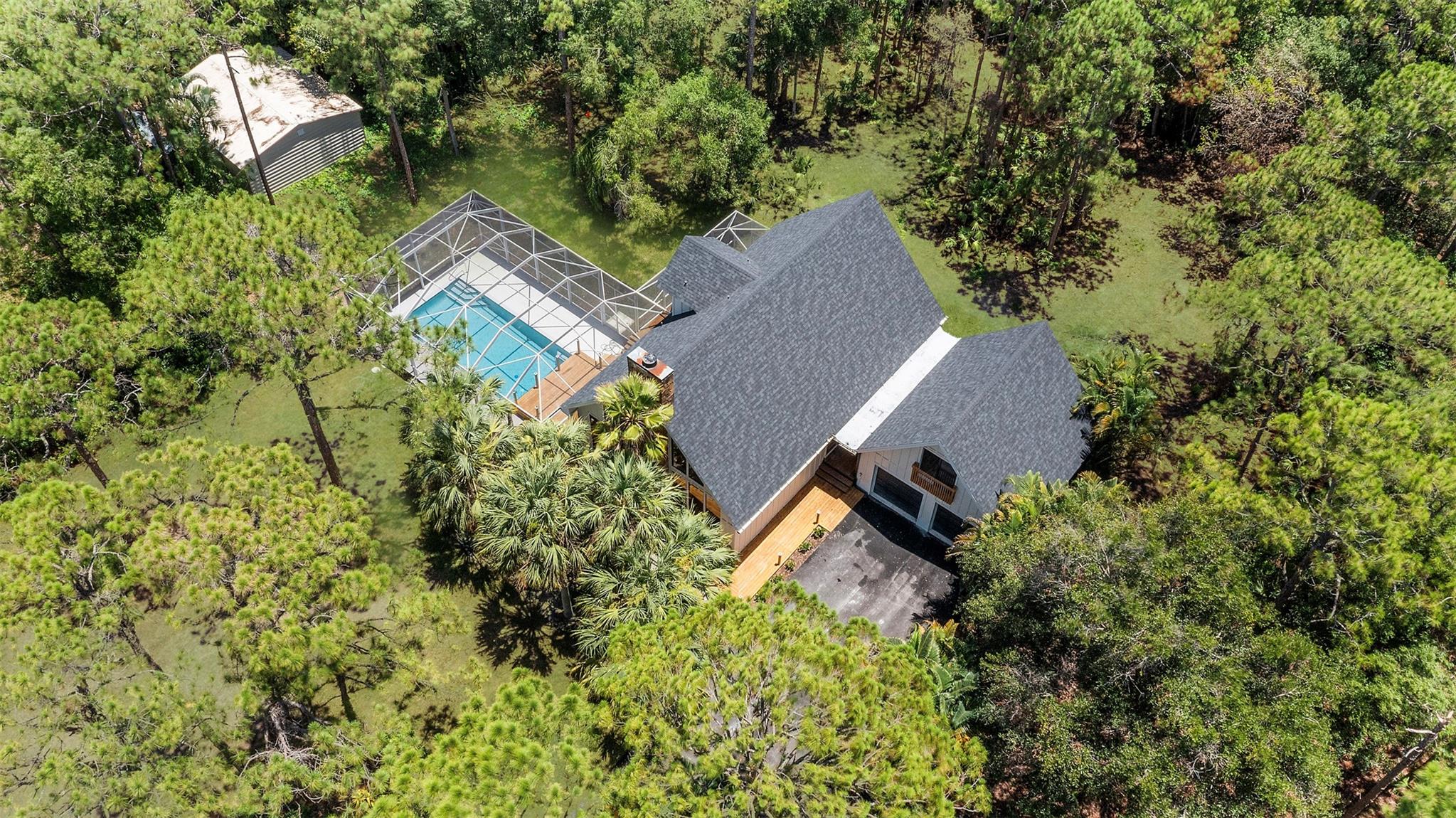 Indulge in the rare fusion of sophisticated design and natural tranquility at this impeccably crafted 2,500 sqft estate, completely remodeled in 2025. This is a private sanctuary, thoughtfully designed for high-end living with a touch of rustic soul. Modern Appliances, New Roof, New HVAC, New Home.
From the moment you arrive, the expansive wraparound porch sets a tone of quiet luxury. Inside, vaulted ceilings and walls of glass bathe the home in natural light, blurring the boundaries between indoor comfort and the lush outdoors.
The heart of the home is a bespoke chef’s kitchen, tailored for beauty and performance, while the bathrooms evoke a luxury spa experience. Step into your private resort: a showstopping pool with a cascading waterfall, tropical landscaping, and open skies.