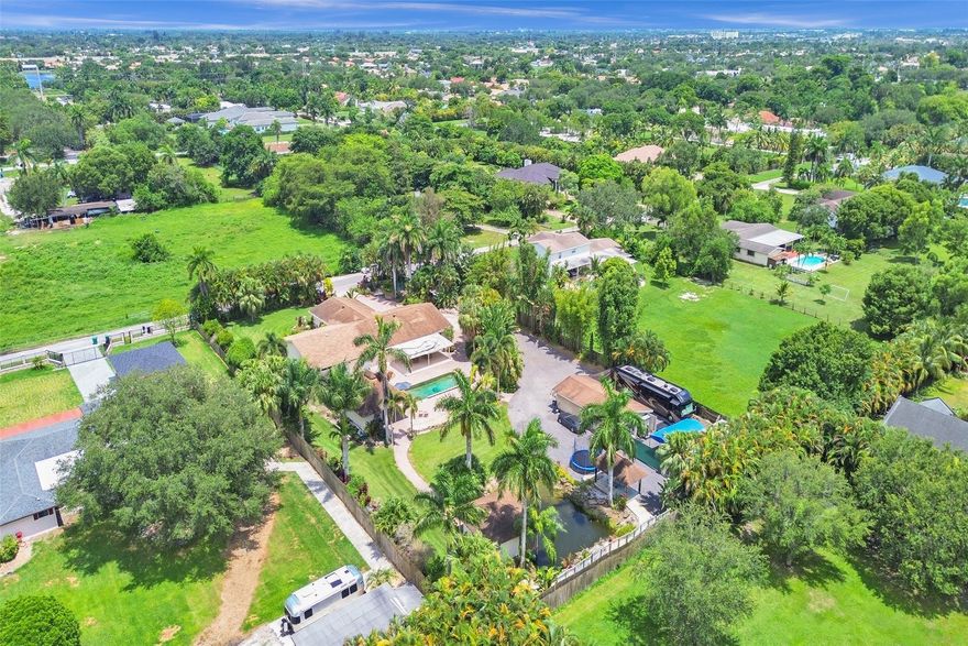 Rare opportunity in prestigious Southwest Ranches. Every inch of this lushly landscaped 1.13 acre estate is utilized, with still endless potential for personal and professional pursuits. This is an outstanding option for contractors, creatives or anyone seeking that work from home lifestyle or expansive multigenerational living. The main house features 5 large bedrooms, 5 full baths. Countless options abound with 2 additional buildings, creating guest room, office or workshop. Enjoy a heated pool and gorgeous tropical sunsets steps from 1 or 2 primary suites. Stroll further west to feed the fish in the “Koi pond” outside the casita. The entirety of the estate is securely fenced. A 2nd hard surface driveway leads to a 20x40 workshop with ample parking for cars, trucks, boats, RVs, etc.