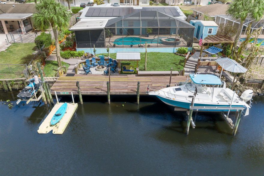 OCEAN ACCESS - Waterfront home - boating, entertaining and year-round Florida enjoyment. Nestled on the St Lucie River, this eye-catching home features a private dock with dual lifts(boat and jetski), floating dock for kayaks, a saltwater pool with raised spa, and expansive outdoor living - perfect for entertaining or quiet sunsets by the fire. Panoramic water and nature preserve views across the river for extra privacy. Bright, open living spaces flow easily to the pool area with pocket sliders off the living and primary. Optional storage area that can easily become a third bedroom under air. 2021 roof and fully paid solar panels to cut energy costs. County-only taxes, electric RV hookup/storage, and convenient proximity to restaurants, shopping and marina/boat launch complete the package