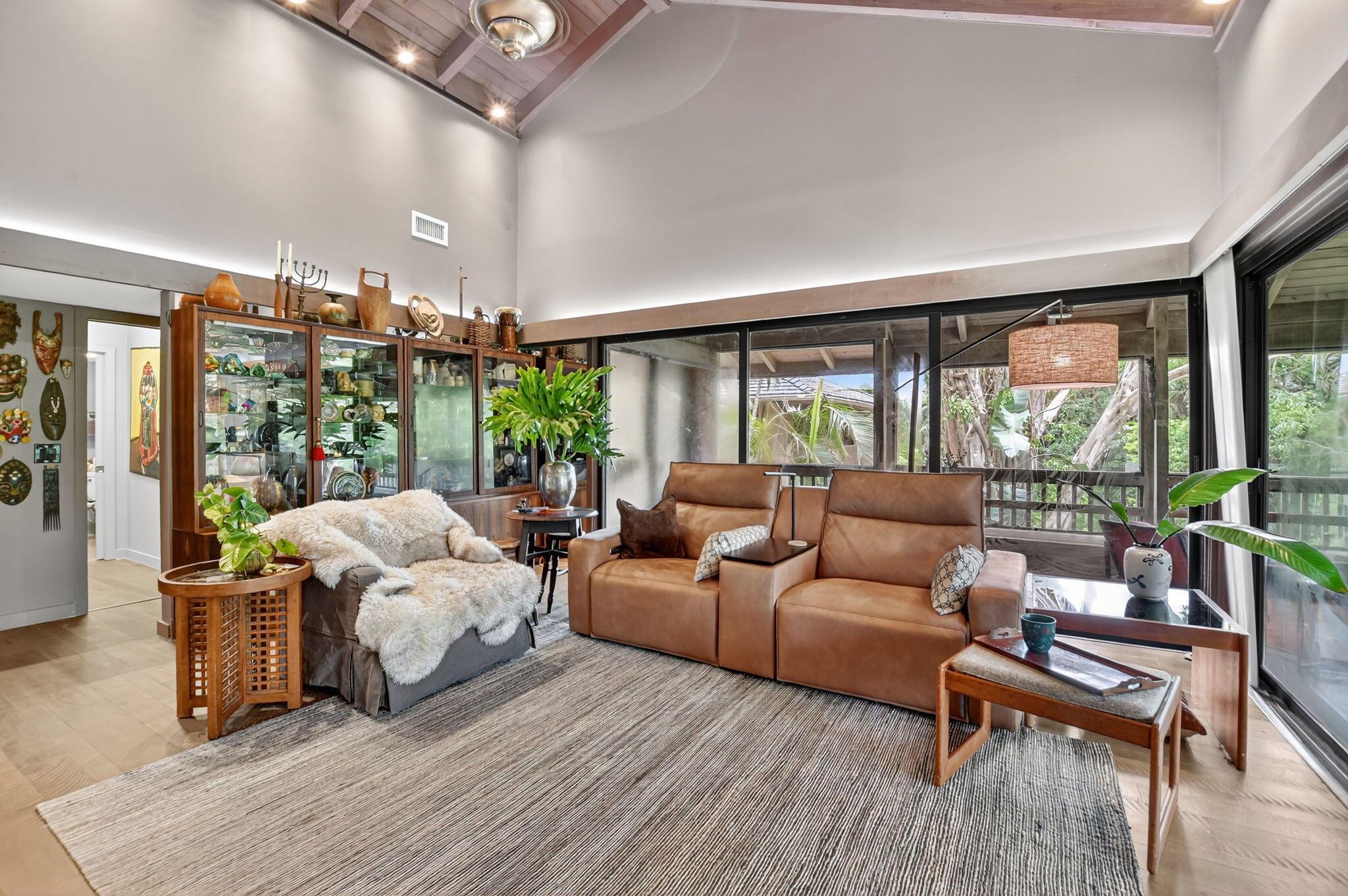 Rare Plantation Colony residence in Boca West's most beautiful enclave. Fully gutted and renovated in 2020-21 with a fresh Boho-inspired vibe, this 2-bed/2-bath second floor unit home features solid wood floors, high exposed-beam cathedral ceilings, updated kitchen and baths, and added closet space. Walls of wrap-around sliding glass doors open to a screened lanai with tranquil water and lush tropical views, creating a private treehouse-like retreat. Other updates include new HVAC and a tankless water heater. Tucked into Plantation Colony's most peaceful end courtyard, with covered parking seamlessly integrated into the landscaping. Residents enjoy a lakefront pool with tiki huts, MORE...