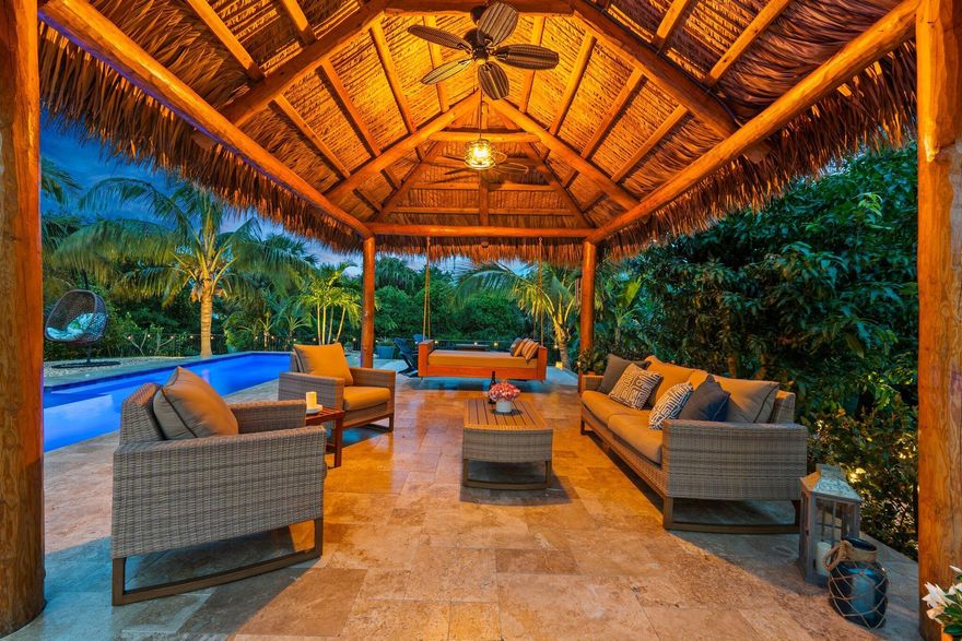 Bohemian Beach Chic meets coastal luxury in this stunning 2021-built retreat! Perched 28 ft above sea level on an oversized lot with only one neighbor, this home offers exceptional privacy in a prime location. Boating enthusiasts will love the coveted 40-ft boat slip at the marina, just a short ride to the Atlantic with no fixed bridges, complete with a 24,000 lb lift. Outdoors, a tropical oasis awaits with a tiki hut, fans, lighting, and a 50-ft heated saltwater lap pool surrounded by sealed travertine decking. The lush landscaping is maintained effortlessly with a timed irrigation system. The thoughtfully designed interior features wall accents, upgraded trim, and plantation shutters in the primary and secondary en-suites. The open-concept living space flows to a screened front porch with solar screens for added comfort. Energy-efficient construction, 4ft aluminum fenced backyard, dog run, and resort-style lighting complete this dream home. Move right in and enjoy paradise!