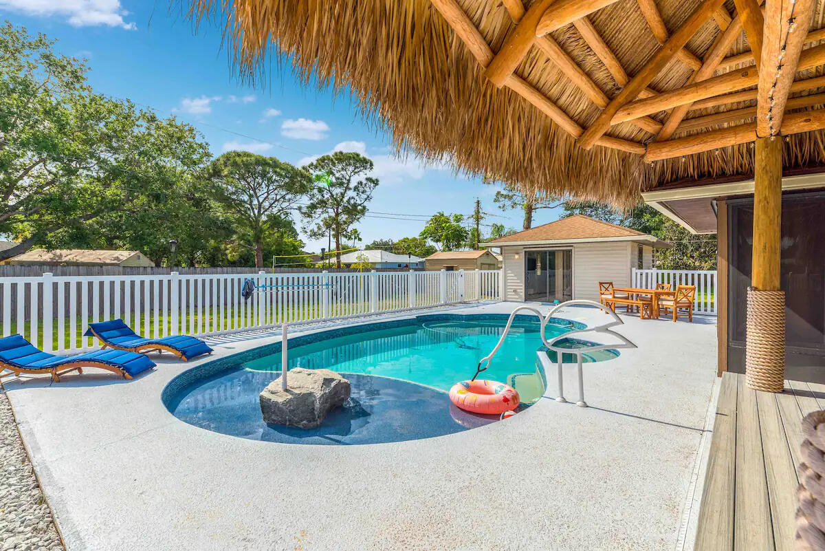 Picture yourself sipping cocktails under swaying palms in your private, sprawling retreat! This breathtaking double lot, nearly half an acre, is a rare gem east of US 1, nestled in a serene, family-friendly neighborhood with NO HOA. Lush mature trees frame an exquisite outdoor tiki living area, perfect for entertaining, overlooking a dazzling pool and spa that promise endless relaxation. The main house boasts 2 expansive bedrooms and 2 luxurious baths, while the charming 1/1 Guest House - ideal for in-laws, teens, or guests - features modern mini-split AC and a tankless water heater, all overlooking the shimmering pool. Brand new 2024 roof, this turnkey AirBnB goldmine is ready to generate income or become your dream home. Don't miss this chance to live the ultimate tropical lifestyle!
