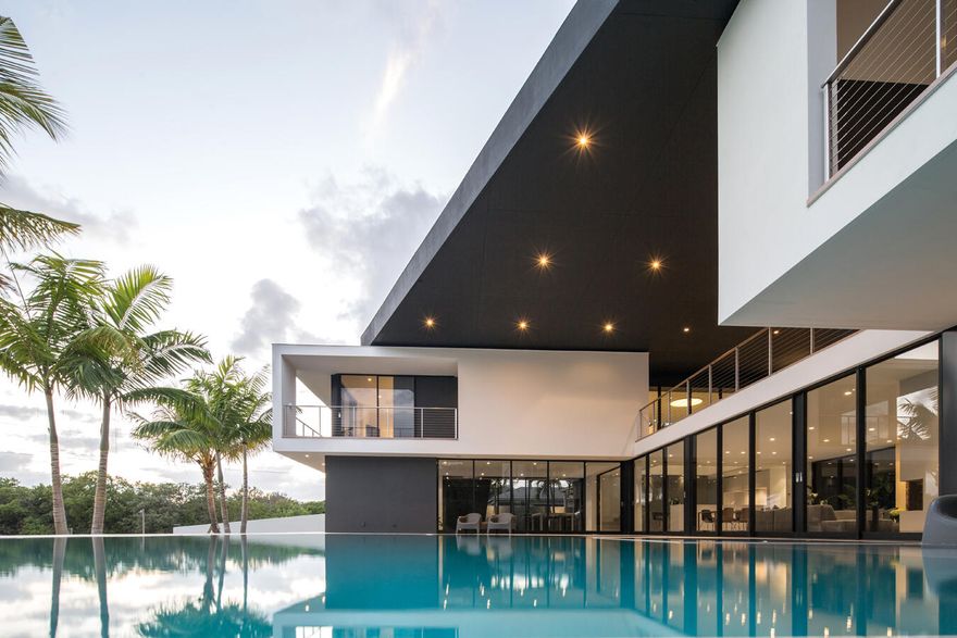 HughesUmbanhowar Architectural Masterpiece on the Loxahatchee River. Featured in Modern Luxury Interiors South Florida and Palm Beach Illustrated. 3 en-suite bedrooms/2 half baths/private guest wing with en-suite flex space. Privacy and modern elegance combine to make this home one of the finest in Jupiter. Situated on a private 0.6-acre lot, this thoughtfully designed estate offers breathtaking water views and deck access from every room. Abundant natural light accentuates the home's clean architectural lines and outdoor connection. With a striking white and gunmetal palette carried seamlessly throughout the interior and exterior, the architecture itself becomes the home's defining artwork. Offered fully turn-key, the home is furnished with custom pieces by B&B Italia, Luminaire and Design Within Reach. The fully outfitted kitchen is complete with custom walnut cabinetry, a Bertazzoni cooktop, Miele appliances, and a dramatic Wagamama waterfall marble island-creating a truly effortless move-in experience. Spanning 5,099 square feet of harmoniously designed living space, the home features meticulous hardware-free, soft-close cabinetry and concealed appliances that allow the kitchen to blend naturally into the surrounding living and dining spaces. A sophisticated architectural lighting plan by Delta Light, thoughtfully layered with recessed fixtures, enhances the home's modern aesthetic and beautifully highlights its clean, minimalist lines. Complementing this design, sleek circulation grills and linear slot diffusers provide optimal air movement while maintaining the home's refined look. The first floor is finished with terrazzo floors with a modern matte finish, while the second floor transitions to warm, refined wood flooring. The kitchen and living areas, framed by Fleetwood telescoping doors, open seamlessly to a spacious recreational family room, outdoor kitchen, expansive outdoor terrace and a beautifully designed EURO edge salt water pool with built in hot tub, offering an elevated environment for both entertaining and quiet relaxation. The second floor hosts three en-suite bedrooms, each with private balconies, showcasing Resysta deck flooring, and stunning water and estate views. The primary suite features a dual-access wet room-style shower adorned with Robern mirrors. In addition, a separate guest wing across the covered terrace includes its own en-suite flex space, complete with a custom Murphy bed and its own spectacular balcony views. Elevating this extraordinary property is a private dock with a 12,000-pound boat lift (including Jet Ski), protective seawall, and easy ocean access-ideal for enjoying the very best of Jupiter's waterfront lifestyle. With its refined design and uncompromising attention to detail, this exclusive home is the epitome of luxury living in South Florida.