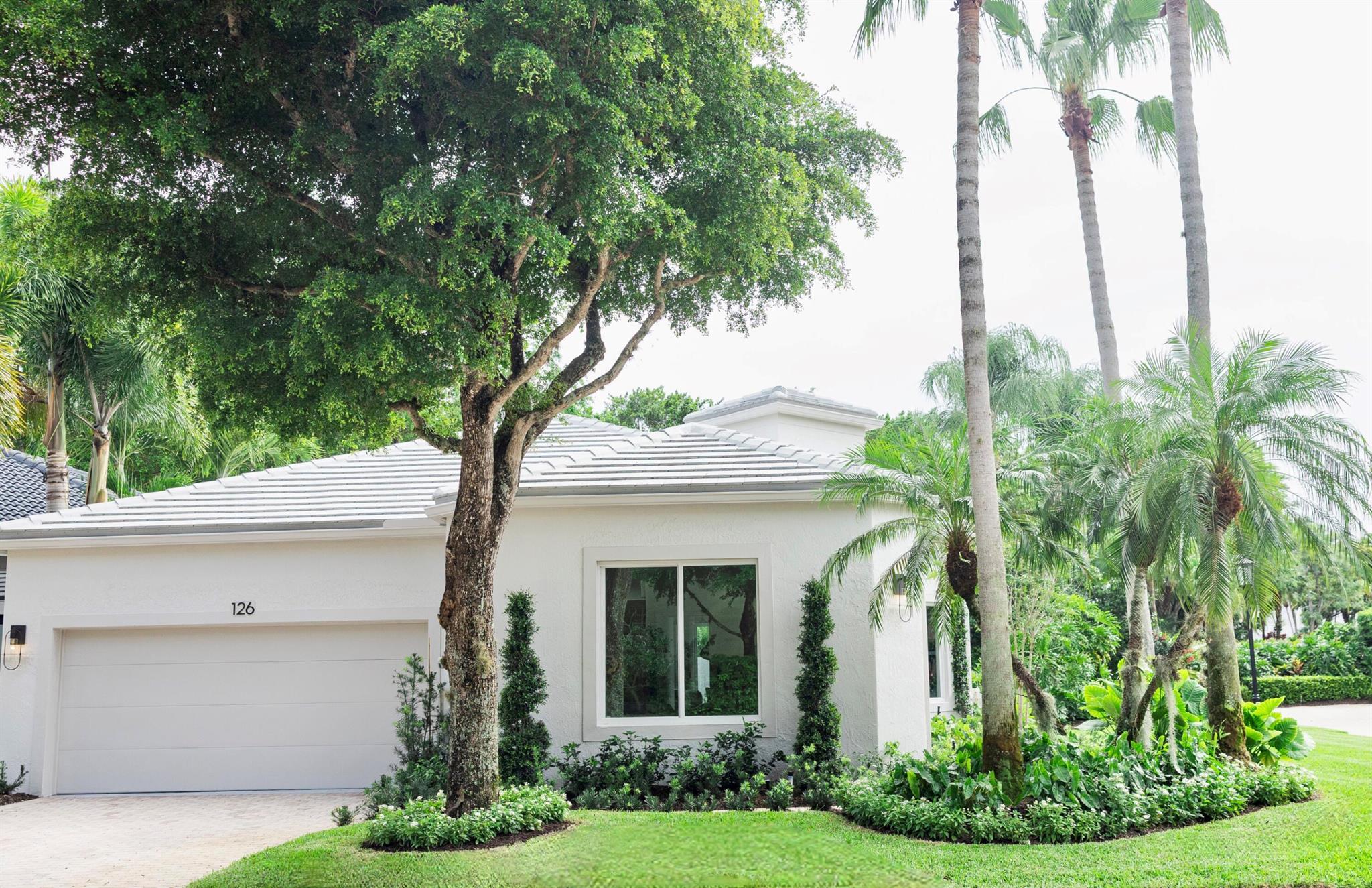 Step into refined living with this completely transformed home on a corner lot in the prestigious Ballenisles Country Club community. With final permit secured, move right in to this turn key designer home. This 3 bedroom residence offers 3 ensuite baths, providing privacy and elegance in a completely redesigned and open floorplan.Twelve foot ceilings throughout create openness and volume, as you enter through 10-foot tall double doors into a newly expanded sunlit living area - featuring 10-foot windows now extending to the floor. With an expansive set of sliding glass doors allowing natural light, one's connection to the backyard sanctuary is enhanced. The ENTIRE home is secured with newly installed hurricane impact windows and doors- including