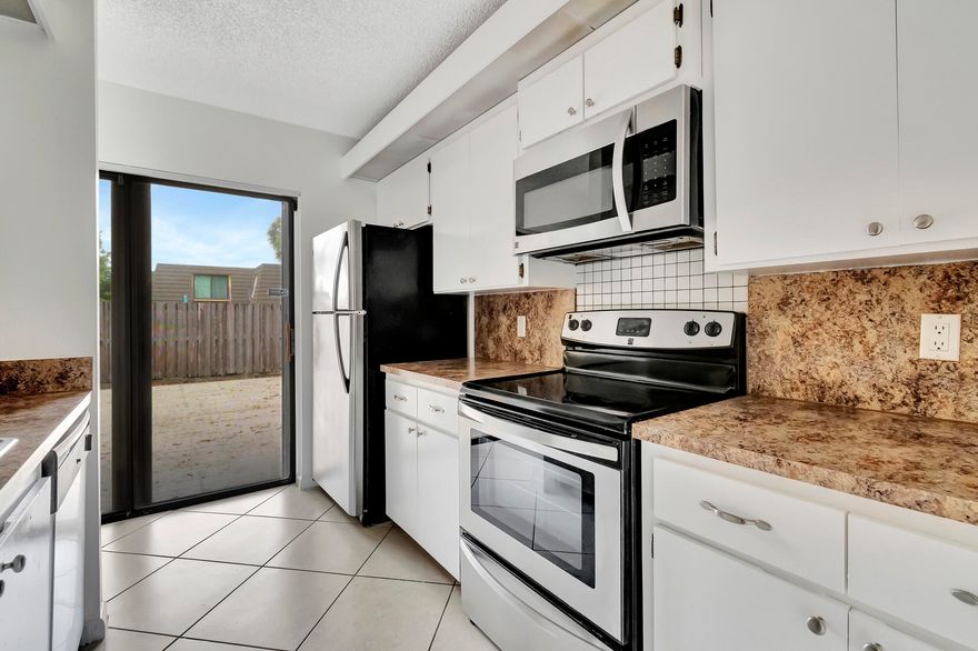 Welcome to your new home in the desirable Village of Sandalwood Lakes! This charming townhome offers a perfect blend of comfort, style, and convenience. As you step inside, you'll immediately notice the inviting atmosphere created by the ceramic tile flooring and updated fixtures throughout. The galley-style kitchen is a chef's dream, featuring stainless steel appliances and an oversized passthrough with a seated bar, perfect for casual dining or entertaining guests. The owner's suite is a retreat unto itself, boasting a private balcony, double closets, and an en suite bath with a step-in shower, providing both luxury and practicality. One of the highlights of this property is the huge open terrace, surrounded by a privacy fence, offering an ideal setting for outdoor entertainment.