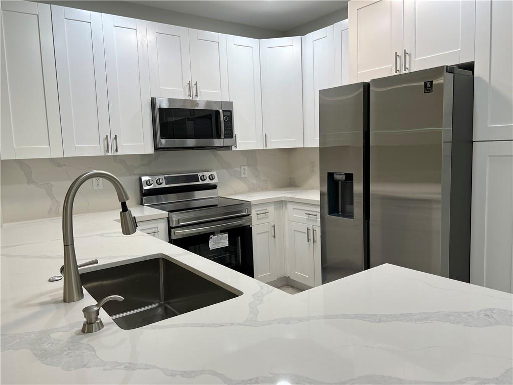 This beautiful one-story, 3-bedroom, 2-bathroom corner unit close to parking is located in the gated community of Villaggio. It features a spacious open floor plan with tile flooring throughout and a private balcony. The unit includes a separate laundry room with a full-size washer and dryer, along with a stylishly updated modern kitchen boasting sleek white cabinets, quartz countertops and backsplash, stainless steel appliances, and LED recessed lighting in both the kitchen and living room. The primary bedroom offers a generous walk-in closet and a renovated en-suite bathroom with double sinks, a soaking tub, and a walk-in shower. The second bathroom is also updated, featuring a walk-in shower, a modern vanity, and quartz countertops.