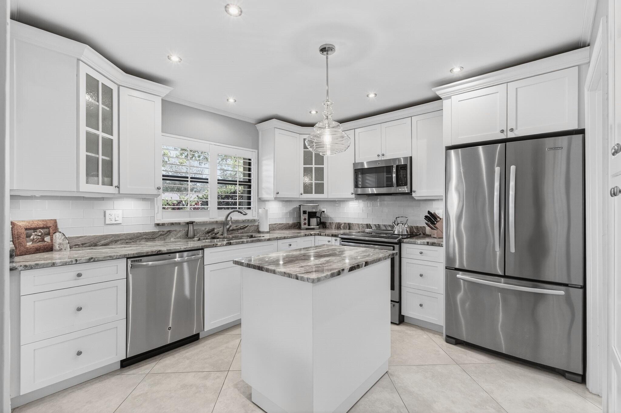 Pride of ownership is evident from the moment you step into this completely renovated 2BR/2BA 1-car garage villa. This corner villa features: Currently renovated kitchen in designer colors with shaker white wooden soft-close cabinets, New SS appliances, pantry, granite counters with subway tile backsplash, and movable kitchen island. AC May 2025, Recessed lighting in kitchen and living room, 24x24 Neutral tile on the diagonal throughout, New windows with accordion shutters, impact sliding glass door in Florida room, knock down textured ceilings (no Popcorn), garage has tile flooring, full-size washer and dryer with laundry tub, plantation shutters on all windows, finished attic with plywood floors and shelving, custom extended driveway recently resurfaced, updated crown molding and 7''