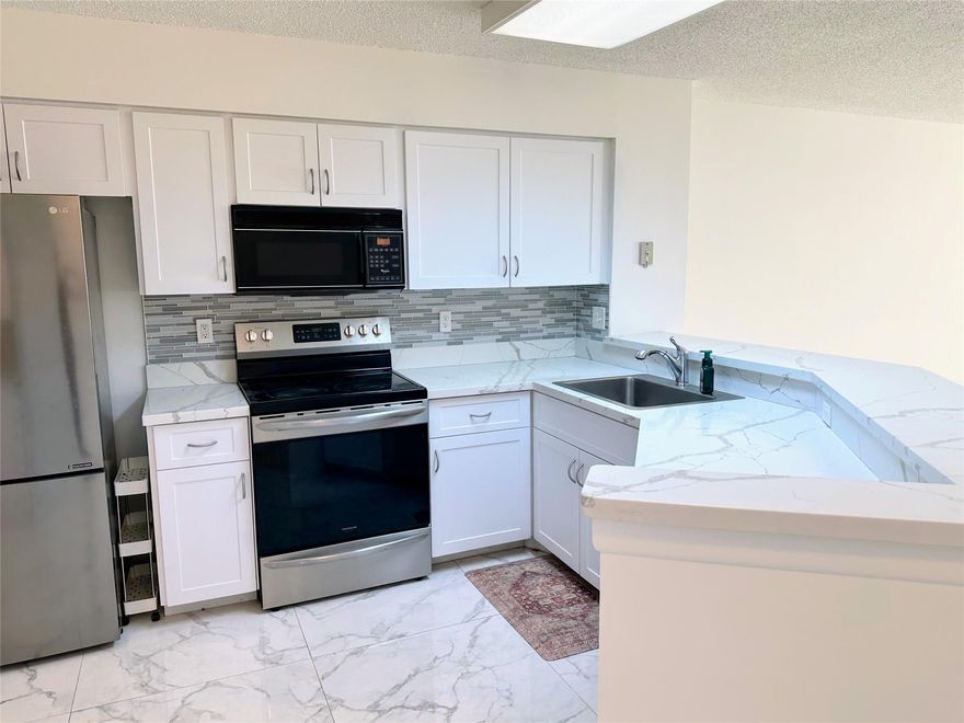 Beautiful and bright 2 bedroom, 2 bath corner unit boasts a screened in balcony with lake views, stainless steel appliances (New Microwave to be installed), quartz counter tops and modern tile flooring throughout. You'll love the full size washer/dryer in unit (New Washer/Dryer to be installed), large walk in closets, and impact windows. Well maintained appliances include Water heater 2019, AC 2023 (Brand New). Well managed community with resort-like amenities: Pool, Hot tub, Barbeque, Clubhouse, Billiards Room, Card Room, Tennis courts, Walking trail and Fitness Center. Just off of Powerline. Close to dining, shopping and 20 minutes to FLL airport. Pet friendly-1 dog or 1 cat under 25 lbs.