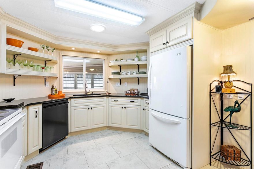 Turnkey Tropical Paradise in Jamaica Bay 55+ Community! Step into your own tropical retreat with this beautifully updated 2-bedroom, 2-bathroom home in the sought-after Jamaica Bay 55+ Community. Designed for comfort and style, this home features updated lap siding with a double roof for durability, along with vinyl flooring throughout except for the kitchen with tile flooring. The remodeled kitchen is a chef's delight, featuring granite countertops, decorative cabinetry, a pantry, and shelving to display glassware and dishes. The spacious master bedroom offers plenty of closet space and a charming barn door leading to the remodeled master bathroom, complete with a tiled shower and decorative vanity. The guest bedroom is equally inviting with generous closet space, while the remodeled