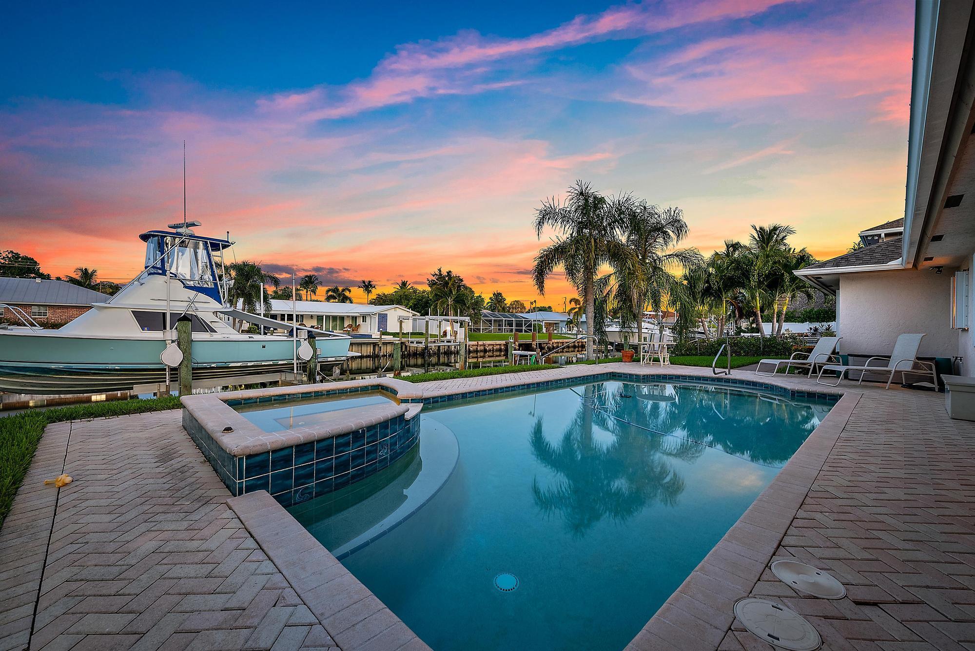 Not only offering 80 feet of Jupiter, Florida's fine water frontage for yourself and your boat, this quaint yet luxurious home is only minutes to many of our water accessible activities and restaurants. Welcoming you into the boater's dream home equipped with a 16k lb boat lift - you're greeted with a bright, open spaced layout of just over 2,000 square feet under air and 3 bedrooms, 3 baths, and a two-car garage. The primary suite of generous size presents you its serene waterfront view, walk-in closet, and just steps outside to your pool and spa. There's an en suite guest bedroom and cabana bathroom to accommodate, host, and entertain your visitors with ease. Roof, Dock and Pool 2004. Boat Lift 2003. 2 new AC Units, New Pool Heater. Accordion Shutters for storm protection.