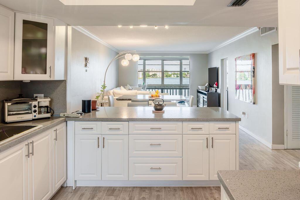 Rarely available 2 bedroom unit with amazing lake views in the desirable Sixth Moorings Condominium. Enjoy stunning, expansive lake views from the living room, Florida room and primary bedroom. The unit boasts a beautifully remodeled open-concept kitchen with white wood cabinetry, sleek gray quartz countertops, and stainless-steel appliances. Hurricane-ready with impact glass windows for added protection. The main living areas feature elegant gray wood laminate flooring, while the bedrooms are finished with durable tile. Includes one assigned parking space, with additional guest parking available. This is a 55+ community with no pets or leasing permitted.