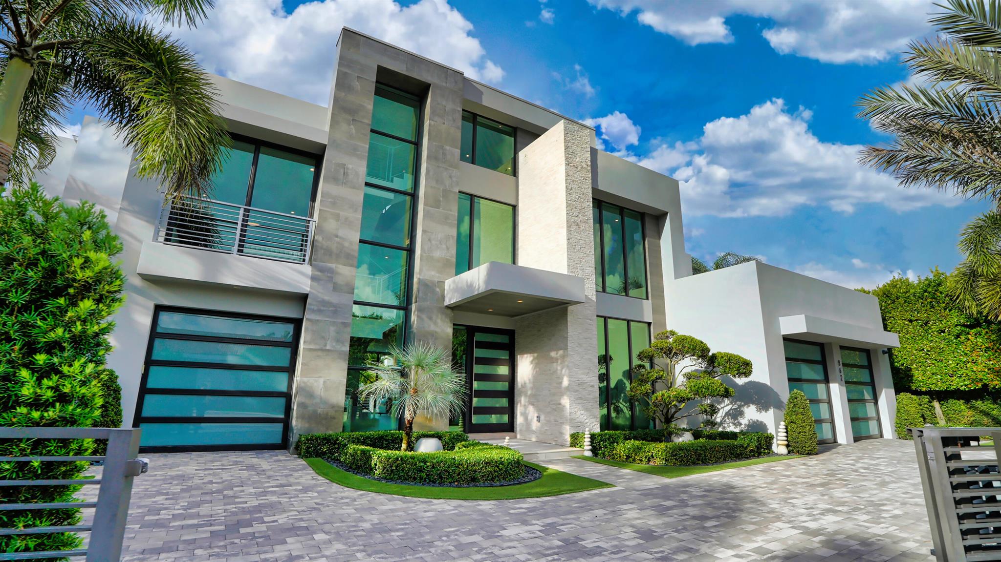 Sleek Modern 3-level Lake Rogers Isles deepwater estate sited on 125 +/- feet of waterfrontage, one off the point with rare Spanish River Park wooded views and originally built by JSB Builders. Light- filled estate with dramatic glass and steel floating staircase highlight with a soaring signature wall up the third floor opens to the great room with fireplace and window walls of glass overlooking the pool and waterway beyond. Gourmet kitchen island kitchen boasts suede finish stone countertops and glass subway tile backsplash, top of line appliance package and walk-in pantry. The dining room features a 1000 bottle glass wine vault to a professional bar. A Family room and adjacent Bedroom suite #5/Office completes this level.