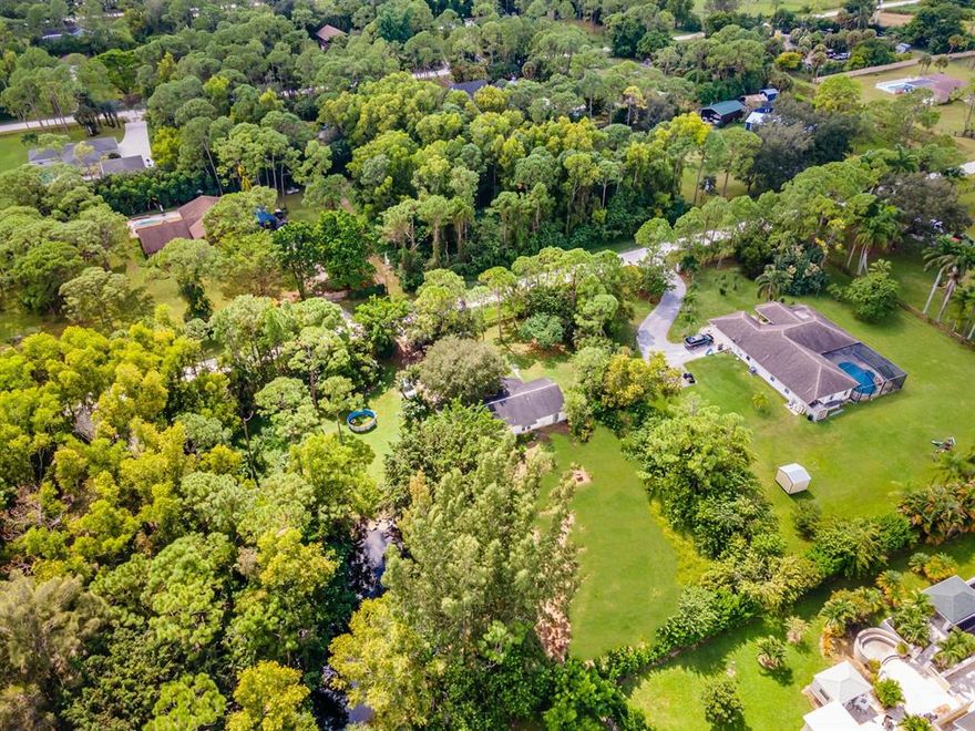 Enjoy the country life on a quiet road with stunning views of Loxahatchee sunrises and sunsets. With a 1.19 acre property, use the space to grow your homestead, or let the kids and animals run! The land is fully fenced with plenty of space to put in a pool and park your large vehicles, build an addition or raise livestock. A pond hosts ducks, turtles, and fish, surrounded by natural landscaping and wildlife galore. The home's garage has been converted to a bonus living space, making a great recreation room or den. CLICK THE VIRTUAL TOUR LINK TO WALK THROUGH THIS HOME!