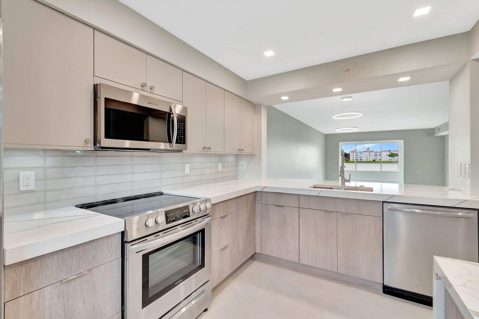 STEP INTO CHIC LUXURY WITH THIS MUST SEE ONE-OF-A KIND, CONTRACTOR DESIGNED CONDO! Completely reimagined and built to be the best in Huntington Pointe, this stunning 2-bedroom, 2-bathroom + den home offers 1500 sq. ft. of elegantly designed living space. From the moment you enter, you'll be captivated by jaw-dropping, unobstructed lake views and an open-concept layout that maximizes space and natural light. The spacious living/dining room with bar seating, flows seamlessly to the under-air lanai. Freshly painted in soothing neutral tones, every inch of this home has been completely renovated, including opening walls and expanding the lanai. The kitchen boasts sleek Euro-style kitchen cabinetry with soft-close drawers, quartz waterfall countertops, rechargeable under mount lighting, and an