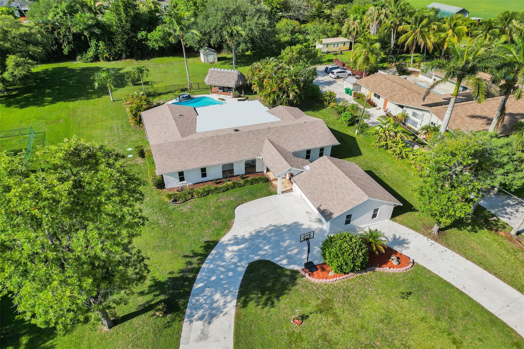 Hidden Gem in West Davie with NEW ROOF, DUAL A/C, & NEW Septic/Drainfield! Nestled in a desirable non-gated equestrian friendly community known for it's private one acre lots, cascading mature trees, & NO HOA. A perfect blend of charm & warmth in this 4 bedroom, 3 bath home with a versatile floorplan, as it has two large master suites. Interior features a large kitchen w/ room for island, sleek counters, stylish backsplash & SS appliances. Modern spa-like bathrooms & cabana bath. Custom accent wall, decorative crown molding, travertine flooring through out, & additional family room. New addition with 2 car garage, covered breezeway & 10 car driveway. Backyard is a true tropical oasis with newly resurfaced pool, rock waterfall, TIKI HUT w/ custom deck, & large covered screened patio!!!