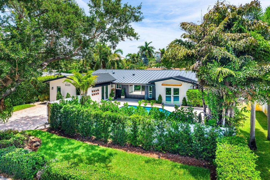 Completely reimagined NE Ft Lauderdale pool home with a new metal roof, paver driveway, and gated entry. Inside, warm wood plank floors flow through 2,400 SF of stunning open living space anchored by a chef's kitchen with gas range, quartz countertops, shaker cabinetry, Moorish tile backsplash, shiplap accent wall, and wine fridge. The primary suite features a private deck, backyard access, and a marble spa bath with chandelier-lit glass shower. All bathrooms are fully renovated with designer fixtures and frameless glass. A terracotta sunroom opens to a composite deck with built-in BBQ center. The saltwater pool is surrounded by lush landscaping and a travertine patio with a motorized awning, and outdoor shower. A custom workshop, and storage sheds round out this exceptional home. EXTERIOR ~ Newer Metal Roof • Impact Windows & Doors • Auto Well Irrigation w/ Water Conditioner/Cleaner • Saltwater Pool • Electric Automobile Charger • Travertine Pavers • Outdoor Hot/Cold Shower • Remote control Retractable Awning • Covered Porch • Security Gates • Full Fenced Property • Built-in BBQ • Tropical Landscaping • New St Augustine Sod • Weather Resistant Privacy Fencing • Weather Resistant Decking • Multiple Custom Designed Storage Sheds • Custom Workshop   HVAC & MECHANICAL ~ 2-zone HVAC • New Electrical Breakers • Brand New LG Washer/Dryer • Security Alarm • Security Cameras & Lighting • Smoke/Carbon Monoxide Detectors   KITCHEN  Gas Cooking • Stainless Appliances • Travertine Backsplash • Quartz Countertops • Thomasville Cabinetry w/ Custom Upgrades • Open and Closed Cabinetry • Under-counter Wine/Beverage Refrigerator • Additional Storage for Wine, Cookbooks, Display • Custom Tile Cooking Backsplash • Peninsula Counter/Breakfast Bar • Full size Pantry  INTERIOR Wide Plank White Oak Wood Flooring • Elfa Custom Closets • Solid-core Interior Doors • Custom Wainscot/Moulding throughout • Crown Moulding throughout • Bathrooms (3 full) completely remodeled  • Energy efficient lighting throughout • Primary Suite w/ 2 walk-in closets • Primary Bathroom w/ Marble Floors, Countertops, Dual Sinks, Frameless Glass Steam Shower • Terracotta Florida room