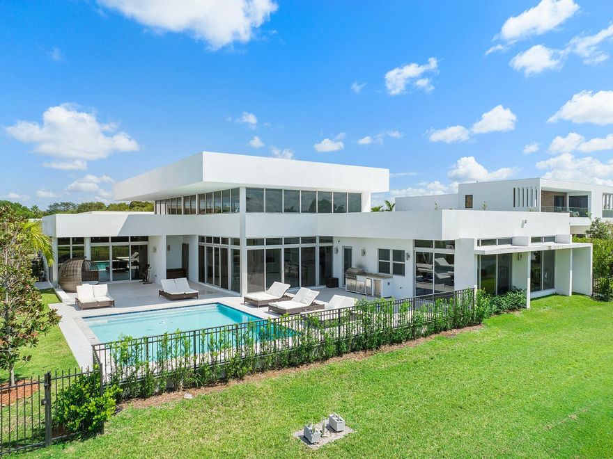 Experience the ultimate contemporary luxury lifestyle in the gated enclave of Botaniko Weston. This exceptional home is ideal for those Buyers craving a modern aesthetic. The arrival experience begins at the private guard gated entrance, through the manicured environs that offer a visual treat of nature and water. The interiors boast 19' ceilings throughout the great room, a gourmet kitchen with natural gas, Wolf and Subzero appliances, a captivating lakeside entertainment room, and a secluded primary suite. Additionally, there are four more generously sized bedrooms with ensuite bathrooms. This single-story lakeside residence has a heated pool, summer kitchen, and a three-car garage. A-rated schools