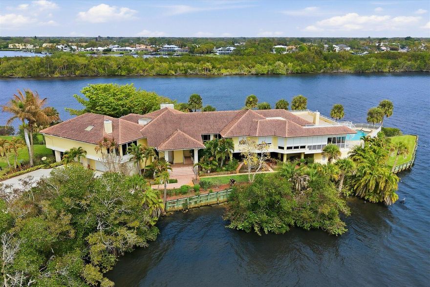 The Peninsula Estate is gracefully set upon more than an acre of land with approximately 650 feet of extraordinary water frontage, offering one of the most private and captivating waterfront settings along Florida's coveted Treasure Coast. Positioned on a rare peninsula within the exclusive gated community of Bay St. Lucie, the property is surrounded by sweeping panoramic views of the St. Lucie River, creating the feeling of a secluded island retreat. The residence encompasses over 8,467 square feet of refined living space, thoughtfully designed to capture the beauty of its surroundings. Elegant marble flooring, expansive living and entertaining areas, a gourmet kitchen, and a distinguished library with fireplace reflect both comfort and sophistication. Walls of glass frame spectacular .. river vistas from nearly every room, seamlessly connecting the interior spaces with the serene waterfront landscape. A separate guest residence offers private accommodations ideal for extended family or visiting guests. The estate's expansive grounds and remarkable peninsula setting present exceptional possibilities for a private family compound, executive retreat, or luxury waterfront sanctuary. Outdoors, a private docks w/30,000 & 10,000lb boat lifts and resort-style pool overlook the tranquil waters of the St. Lucie River, completing this extraordinary waterfront offering. The Peninsula Estate represents a rare legacy property where privacy, scale, and natural beauty converge. Additional details and property information available in the MLS.