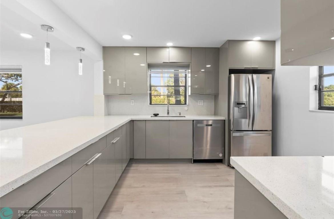 STUNNING, FULLY REMODELED FIRST-FLOOR CONDO WITH LUXURY FINISHES!This one-of-a-kind unit boasts a gorgeous open-concept design with a quartz island and extended bar area, complemented by stainless steel appliances. High vaulted ceilings with LED flush lighting illuminate the main living areas, creating a bright and spacious feel. Enjoy the convenience of a separate laundry room with full attic access, a dedicated office space, ample storage, and sleek quartz countertop Elegant flooring flows seamlessly throughout the home adding a designer touch.