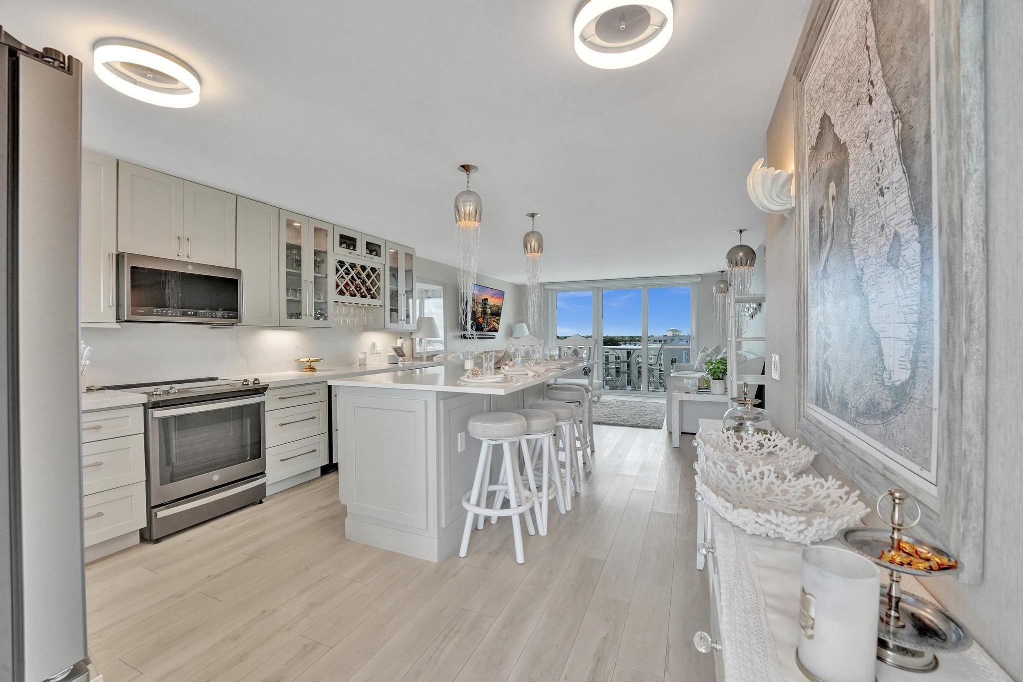 Live the Florida Dream in Style This stunningly renovated 2-bedroom, 2-bathroom condo offers breathtaking panoramic views of the Intracoastal Waterway and the Atlantic Ocean, blending the best of coastal living with modern elegance. Designed by the renowned Palm Beach designer, Jeanne Michelle, every detail of this residence has been meticulously crafted for both style and comfort. Step into a coastal modern oasis, fully furnished and turnkey, ready for immediate enjoyment. The spacious kitchen, perfect for entertaining, features a large island and striking jellyfish pendant lights, while grasscloth wallpaper and charming shell sconces create a welcoming atmosphere. With impact windows throughout and remote-controlled blinds, you'll enjoy both beautiful views and comfort.