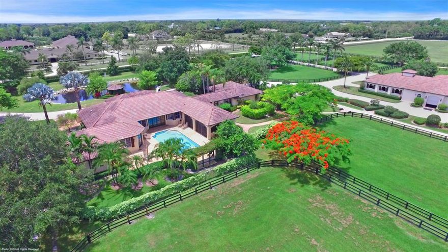 World-class equestrian estate located in the South End of Wellington just minutes from Palm Beach International Equestrian Center, Global and International Polo Club. On over 10 acres, the impeccable facility features a main barn with 14 stalls, wide aisles with Chicago Brick, and tongue and groove ceiling. Additional barns with storage and staff quarters brings the facility stall count to 24 stalls. The main residence boasts 4 bedrooms, 4 and a half bathrooms and features an expansive master suite with his and her baths and walk in closets. Marble flooring and exposed beams are present throughout the home that includes a gourmet kitchen with professional gas range. Enjoy the utmost in outdoor living with an expansive covered patio overlooking the paddocks & travertine decked pool/spa.