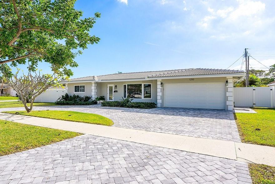 This beautiful home is located east of 12th Ave., nestled between the Cove & Lighthouse Point, surrounded by multimillion dollar waterfront properties, with no HOA! Impeccably designed and maintained, this residence boasts an open concept design that seamlessly connects the living, dining & kitchen areas, creating the perfect space for relaxation and entertainment. The kitchen includes granite counter tops, wood cabinets, a center island and stainless steel appliances. Both bathrooms have been updated and the flooring is engineered hardwood throughout. Additional improvements include: Impact windows & doors, separate laundry room, brick paved circular driveway, 2 car garage and fully fenced corner lot. The screened in porch supplies an abundance of natural light creating the perfect oasis!