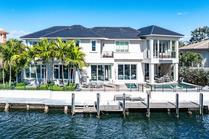 A rare opportunity to own a true custom waterfront estate in the prestigious enclave of Boca Bay Colony, privately positioned on a quiet cul-de-sac just one estate from the point, offering commanding views of both the Intracoastal Waterway and the canal.
This modern architectural masterpiece features 117 feet of deepwater frontage, no fixed bridges, and direct access to the Atlantic Ocean—ideal for serious yachting enthusiasts. Designed and built with uncompromising attention to detail by Terry Cudmore, with architecture by Randall Stofft, the residence seamlessly blends refined luxury with exceptional functionality.
Upon arrival, a dramatic two-story foyer with a glass-railed staircase sets the tone for the home's elevated design. Soaring volume ceilings, marble flooring, and floor-to-ceiling glass flood the interiors with natural light while framing elegant water views throughout.

The main living areas flow effortlessly into the chef's kitchenan entertainer's centerpiece featuring Thermador appliances, dual dishwashers, refrigerator drawers, warming drawer, custom pull-out pantry, and illuminated crystal quartzite countertops with dimmer-controlled lighting. Gas service is available on the street and can be easily connected if desired.
The first level is thoughtfully designed for both entertaining and everyday living, offering a private theater room with five TVs and centralized control, a versatile club room (plumbed for easy conversion to a secondary suite), a refined office with custom floor-to-ceiling built-ins, and a striking powder room adorned with panda marble. A full wet bar with leathered marble countertops, wine refrigeration, custom aquarium, and a cabana bath with secondary laundry complete the space, along with seamless indoor-outdoor connectivity.

The second level is constructed entirely of concrete for superior strength and sound insulation. Four spacious en-suite bedrooms provide privacy and comfort, including a grand primary retreat featuring custom wood built-ins, morning bar, private balcony, dual walk-in closets, and a spa-inspired bath with book-matched marble walls, soaking tub, and dual vanities. Wood flooring adds warmth to the bedroom suites, while marble continues through the common areas. Additional highlights include a poker/lounge room with marble built-ins and instant tankless hot water. Outdoors, enjoy resort-style waterfront living with a heated saltwater pool and spa, expansive entertaining terraces, summer kitchen with built-in BBQ, and a private dock accommodating up to a 60-foot vessel. A Japanese clay tile roof ensures durability and minimal maintenance.

This smart home is fully equipped with Crestron automation, elevator, whole-house generator, central vacuum, self-cleaning water filtration system, multi-zone HVAC, comprehensive security system, and meticulous infrastructure throughoutdelivering luxury without compromise.
This is not a builder-grade home. This is a true custom waterfront estate, designed for those who demand privacy, craftsmanship, and direct ocean access in one of Boca Raton's most coveted boating communities.