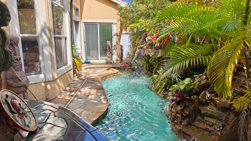 Welcome to your tropical paradise in the exclusive and highly sought-after Heron Bay of Parkland.  Home features three bedrooms, two full bathrooms, a two-car garage, a custom pool oasis with grotto caves and waterfalls and a concrete roof covered patio tiki bar with bbq and mini fridge perfect for entertaining. View the oasis from the livingroom, kitchen, primary bedroom and 2nd bedroom. Vaulted ceilings. Separate laundry room. Original roof and ac. No issues with either- everything works great.  Community great for families with beautiful pools, fitness center, pickleball, tennis, outdoor playgrounds, natural lakes galore, ballroom, business center, full appliance stocked outdoor kitchen/bar area at main pool. Low HOA!