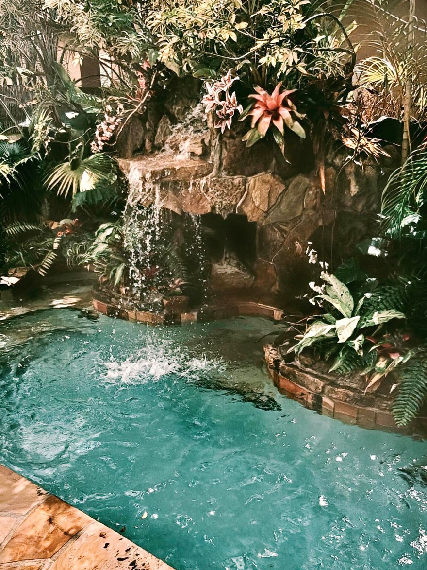 Welcome to your tropical paradise in the exclusive and highly sought-after Heron Bay of Parkland!  Home features three bedrooms, two full bathrooms, a two-car garage, a custom pool oasis with grotto caves, five sitting cut outs, waterfalls, and a concrete roof covered tiki bar with bbq and mini fridge perfect for entertaining! View the led lit waterfall oasis from the living room, kitchen, primary bedroom and 2nd bedroom. Corner lot, Vaulted ceilings. Separate laundry room. Original roof and ac. No issues with either- everything working great!  Community amazing for families- gated, beautiful pools, fitness center, pickleball, tennis, outdoor playgrounds, natural lakes galore, ballroom, business center, full appliance stocked outdoor kitchen/bar area at main pool. Low HOA!