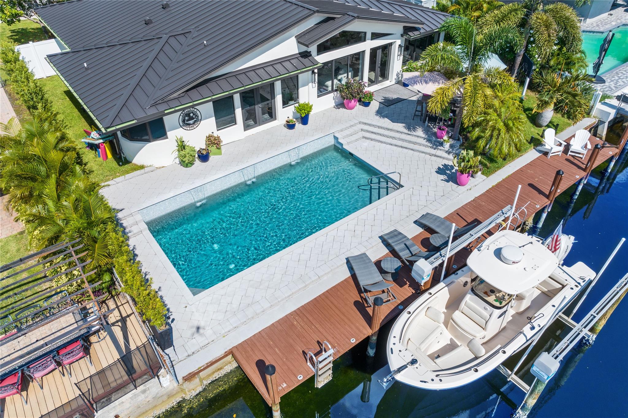 Fully remodeled waterfront estate with 70’ frontage for quick ocean access. This vibrant coastal oasis features vaulted ceilings, expansive living areas, and a chef’s kitchen with quartz waterfall island, gas appliances, wine cooler, microwave drawer, and custom cabinetry, flowing into a sunlit family room. Formal living and dining rooms complement the open design. The primary suite offers pool deck access, spa-inspired bath with freestanding tub, and custom walk-in closet. Outdoors: refinished pool with salt system, lush landscaping, and entertainment space. Additional highlights: impact windows/doors, new roof, water heater, 2-car garage, and laundry room. Ideally located less than 10 minutes to Pompano Beach.