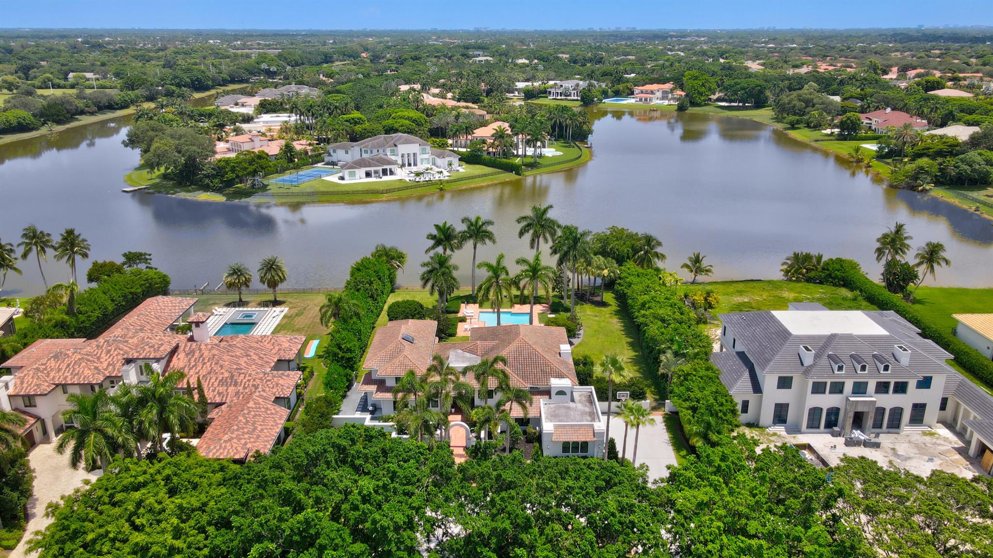 One of the finest renovated acre estate lake homes in south Palm Beach county under $10m. Privacy, space and security highlight this special gated community and lifestyle with classic mature trees and landscaping. A two story entry foyer opens to a dramatic great room, which overlooks the backyard pool, patio and lake. The main first floor of oversized porcelain tile, features an upgraded kitchen with eat in area, dining, media area, office, separate club/entertainment room, exercise room, a full bedroom suite, and full three car garage. Two separate second floor wings consist of four en-suite bedrooms in addition to the spacious primary suite with balcony access and a secondary office media room. See MORE for additional details.