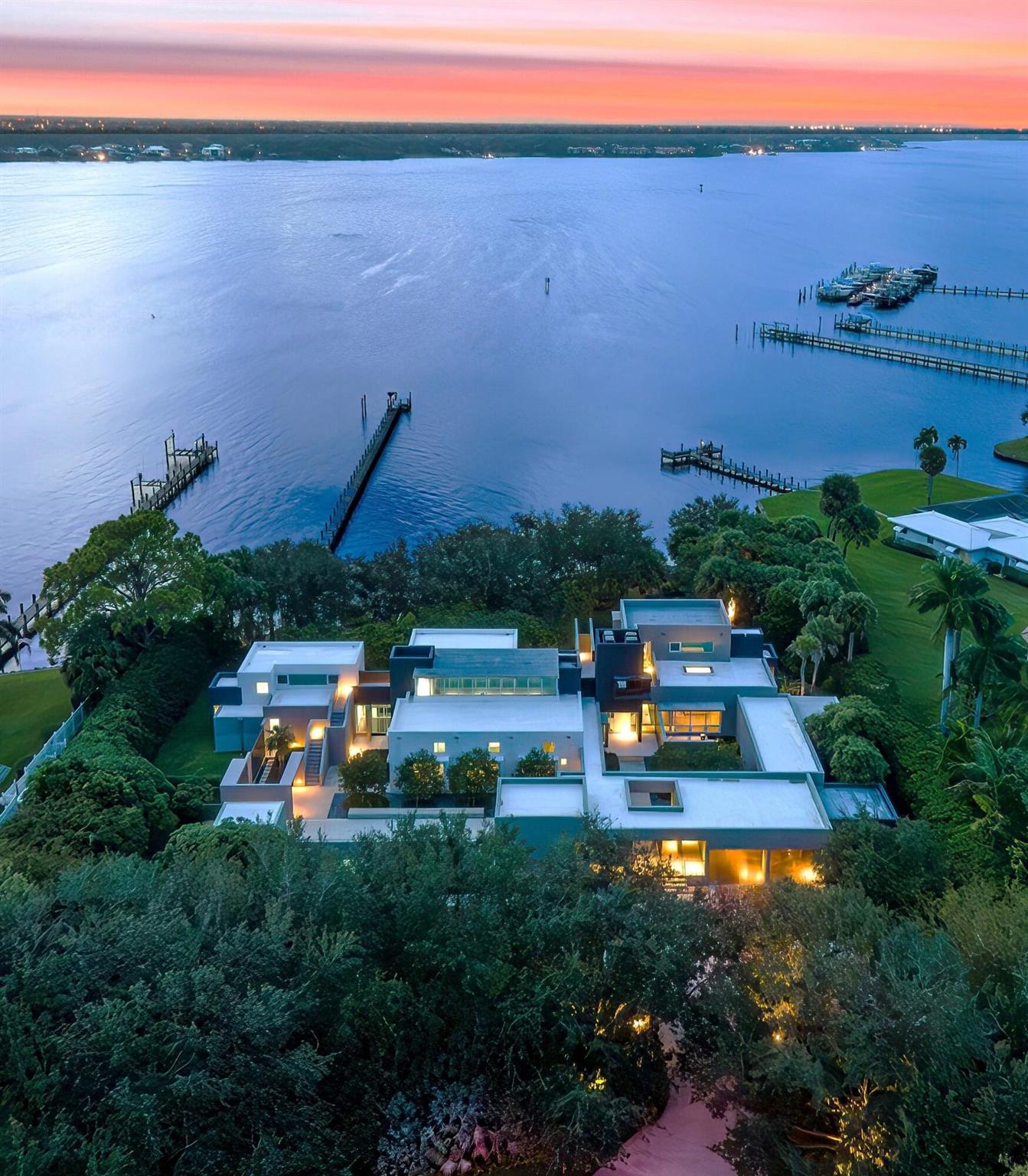 Set on an expansive double riverfront lot, this extraordinary residence boasts over 200 feet of protected shoreline, ensuring privacy, tranquility, and an intimate connection to nature. With unobstructed, sweeping views of the St. Lucie River, the home serves as a front-row seat to the spectacular beauty of panoramic sunsets that transform the sky into a canvas of vibrant colors each evening.This 7,500 sq ft modern masterpiece is a harmonious blend of cutting-edge design and the serene allure of waterfront living. Its striking architecture and floor-to-ceiling windows frame the river from nearly every angle. The residence radiates contemporary elegance while remaining firmly rooted in the natural beauty of its surroundings. Designed with seamless flow connecting to the outdoors,