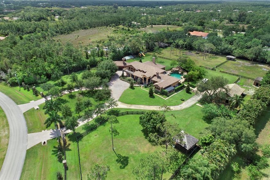 Fully Automated Ranch Estate Smart Home  situated on 5.4 dry acres fenced in with private gates. The spacious 5 bedroom, 5 1/2 bathroom Main house with 5 car garage is designed to entertain with gourmet chef's kitchen featuring gas range, electric range, wall oven, warming drawer, 2 dishwashers, 2 sinks, ice maker, wine refrigerator, beverage refrigerator, butler's pantry and walk in pantries. The family room with open floor plan boasts a large fireplace and bar. State of the art 12 seat movie theater is the perfect place to relax.  The master suite has a fireplace and large his and hers walk in closets. Resort tropical pool overlook rambling fenced paddocks, 4 barns and grooms quarters. Top Smart home technology with security. Impact glass, full house generator, water filtration and more.