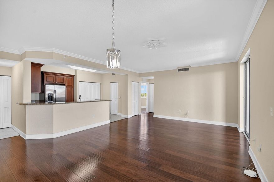 Spanning approximately 1,460 square feet under air, plus a large covered balcony ideal for morning coffee or evening relaxation, this light-filled residence features a desirable split-bedroom floor plan designed for both privacy and functionality. Two of the bedrooms overlook tranquil lake views, while the penthouse positioning provides an abundance of natural light and added privacy. The upgraded kitchen is beautifully appointed with granite countertops, extensive cherry wood cabinetry, pantry storage, GE appliances and a large double-sided stainless steel sink.  Interior features include laminate and tile flooring throughout, crown molding, oversized baseboards, in-unit washer and dryer, generous closet space including a walk-in closet in the primary suite, coat closet, and additional linen storage. The spacious primary suite serves as a true retreat, complete with a large walk-in closet and an ensuite bathroom featuring dual undermount sinks, a soaking tub, and separate walk-in showerAdditional highlights include two dedicated indoor parking spaces — a rare and valuable feature — along with ample guest parking for visitors. Residents enjoy access to resort-style amenities including three swimming pools, jacuzzi, fitness center, basketball court, and beautifully maintained grounds. Conveniently located just minutes from beaches, shopping, dining, major highways, and everyday conveniences.  Whether you are seeking a full-time residence, seasonal escape, or investment opportunity with immediate rental potential, this exceptional penthouse offers the perfect combination of space, location, and lifestyle.