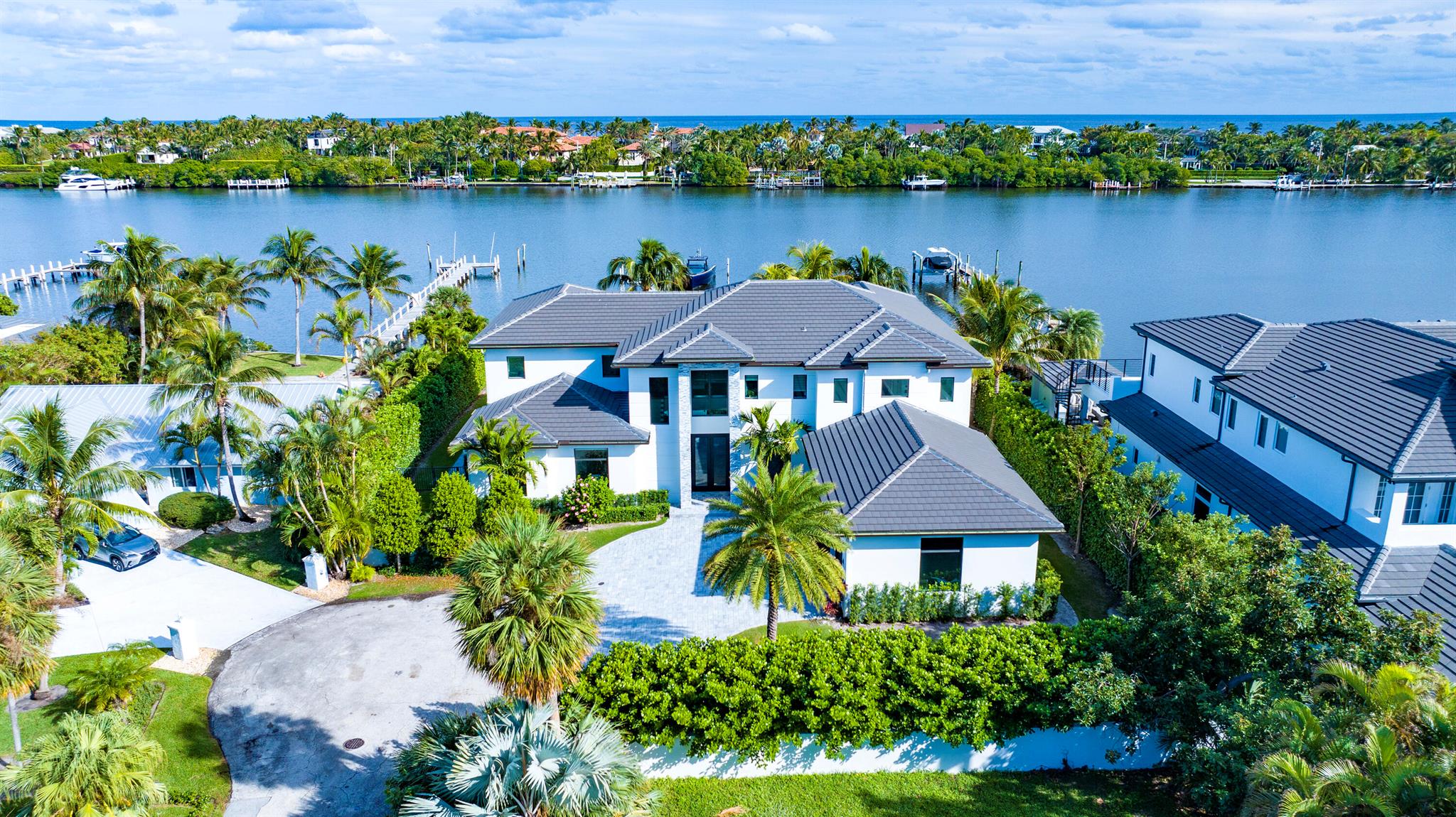Offering awe-inspiring water vistas, this contemporary Hypoluxo Island residence, a 2021 new-build on a quiet cul-de-sac, features 120-feet on the Intracoastal with a dock, perfect for boaters. Form, function and design are its architectural hallmarks, and outside, the loggia and summer kitchen overlook an arresting infinity-edge pool with a sun pad and spa, flanked by dramatic fire bowls.