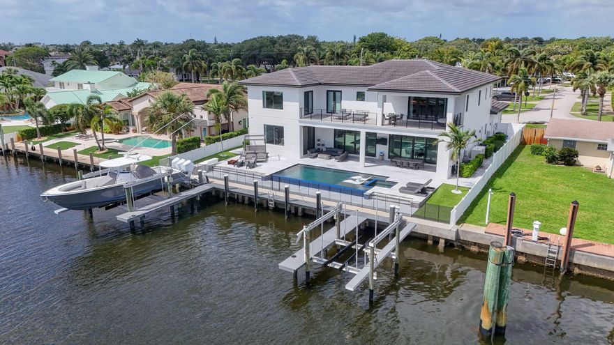 Experience the pinnacle of waterfront living from this exceptional two-story Intracoastal estate, offering over 5,300 square feet of exquisitely designed living space. Privately situated on an expansive .28-acre lot, this remarkable "boater's dream" boasts 90 feet of direct waterfront, a private dock, dual lifts, and unobstructed access to open water with no fixed bridges. Newly constructed in 2021, this custom residence was thoughtfully designed with uncompromising craftsmanship and a seamless blend of modern sophistication and relaxed coastal elegance. The open-concept floor plan captures breathtaking water views from nearly every room and features 4 bedrooms plus a den/office, 5 full baths, and two luxurious primary suites—ideal for multigenerational living or hosting in style. A private elevator adds both convenience and refinement. At the heart of the home, the expansive chef's kitchen is a statement of both form and function, showcasing custom cabinetry, premium Thermador appliances including a double oven, six-burner gas range, two dishwashers, dual quartz islands, and a spacious walk-in pantry—perfectly suited for both everyday living and grand-scale entertaining. The primary suite is a true sanctuary, offering an enormous balcony (accessible by all 3 upstairs bedrooms) with sweeping NPB Waterway views, 2 massive walk-in closets with California Closet built-ins, and custom ceiling detail that adds warmth and architectural distinction. The spa-inspired bath is nothing short of extraordinary, featuring a grand double-entry shower, oversized soaking tub and elegant his-and-her vanities, and 2 water closets. An impressive array of designer finishes and enhancements elevate the home throughout, including wide-plank wood flooring, custom built-ins, curated wall coverings, a striking glass-railed staircase, dual laundry rooms, tankless water heater, whole-house generator, impact windows and doors throughout, reverse osmosis water system, custom lighting, and California Closets in every room—including the garage. Step outside to your private resort-style oasis. Framed by sandblasted marble pavers, the outdoor living space is nothing short of spectacular, featuring an oversized infinity-edge pool with spa and sun shelf, artificial turf, covered patio with tongue-and-groove Synergy wood ceilings, outdoor shower, and a fully equipped summer kitchen. The dock is outfitted with two boat lifts (16,000 lb. and 24,000 lb.) and electric pedestals with both 30-amp and 50-amp service. This extraordinary North Palm Beach Waterway residence offers a lifestyle beyond compare—where luxury, comfort, and world-class boating converge.