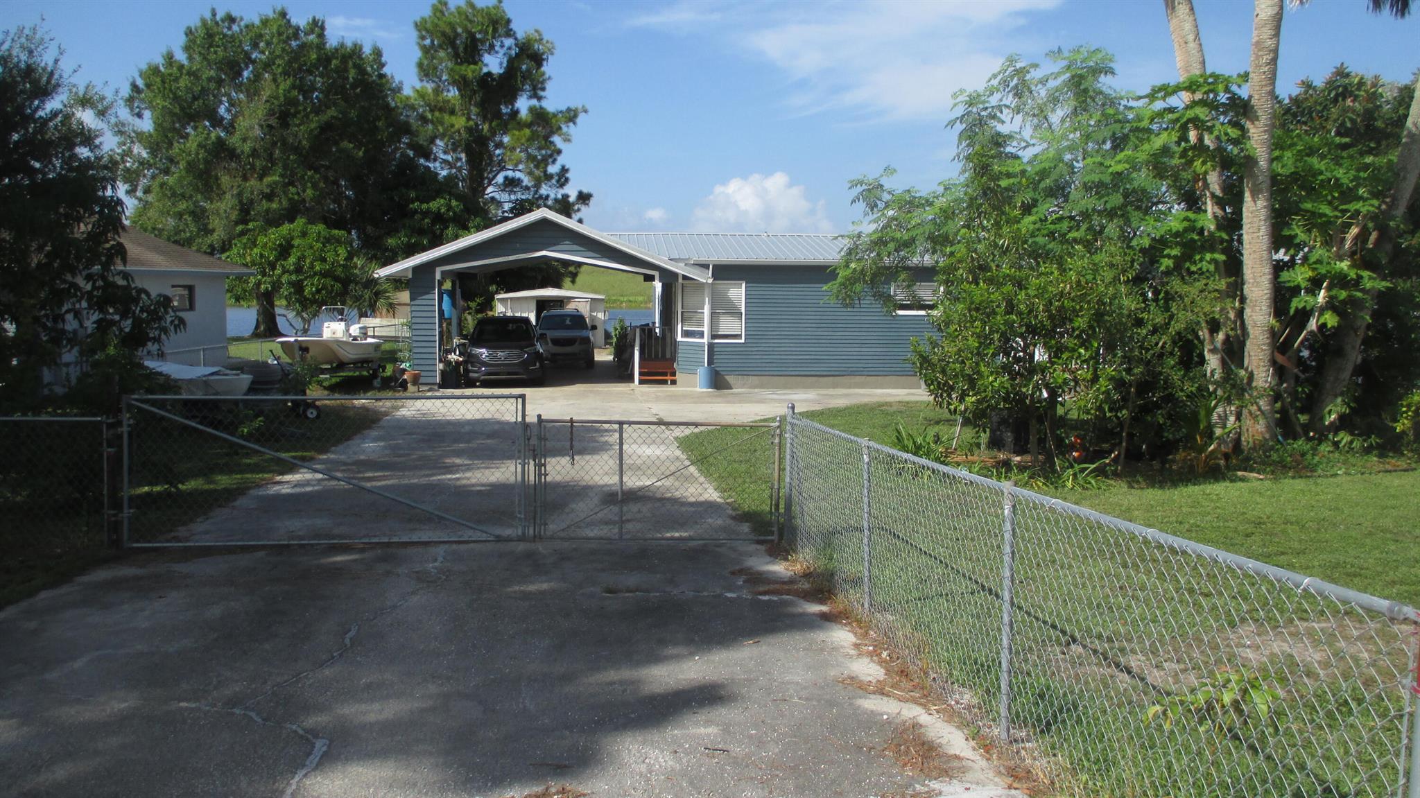 Waterfront on the wide part of the rim canal with access to the Bass Fishing Capital, Lake Okeechobee just a few minutes away. Dock your boat right out back! Just shy of 1/2 acre of your own fenced in land with no hoa. Perfect for an in home business or craftsman/woman as it has a 14 x 25 metal outbuilding, too! RV's, Boats? Bring em! You've got a high carport for your cars and toys! This 3 bedroom, 3 full bath home has a 2021 Metal Roof, remodeled master bathroom, wide open living room and family room with a gorgeous view of rim canal! The Florida room adds even more space for entertaining and if you want to add a pool, you have plenty of room and a cabana bath already in place that you can access from the backyard. It's time to relax and enjoy life!