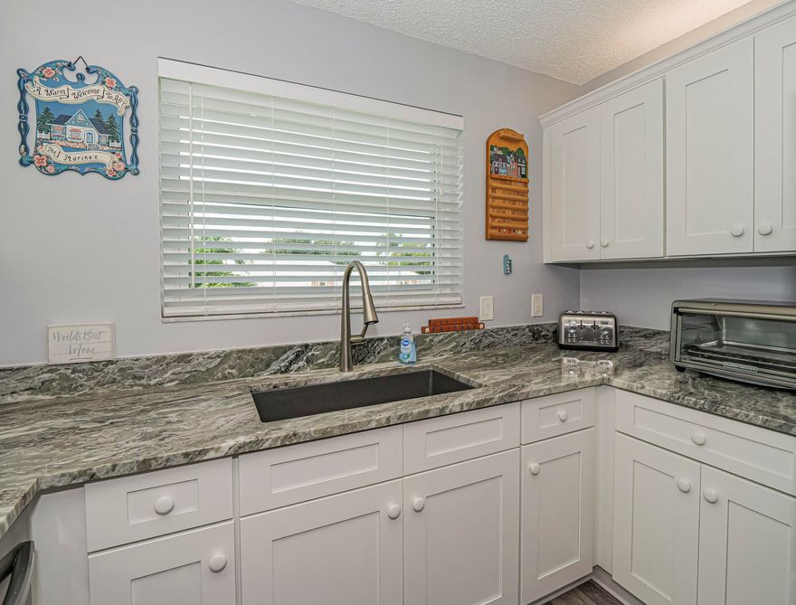 NO HOA fees for the first 3 months is a good reason to see this bright refreshed condo with a fantastic long lake view. The kitchen boasts new high end appliances, granite countertops and LVP flooring.  The living area with cathedral ceilings has new carpeting and is located across from the main clubhouse with tennis and pickleball courts. Impact windows and accordion shutters and a guarded gate insures peace of mind.  1 pet up to 25 lbs.  2 community pools, 2 clubhouses, a library, kayak storage, and direct river access, perfect for those who love an active lifestyle.  Seller is motivated. Furniture is negotiable