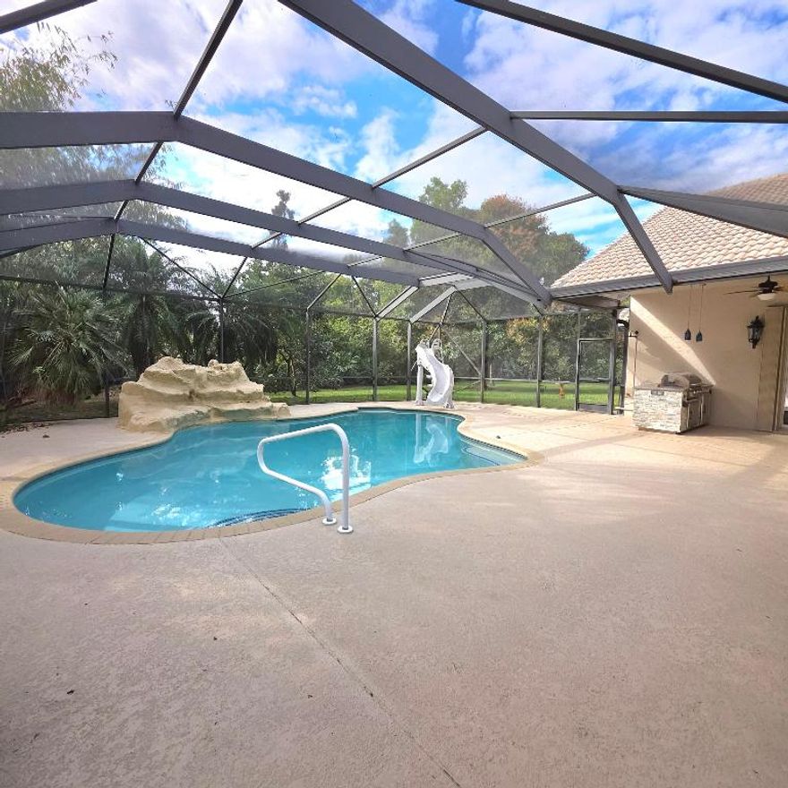 Presenting a rare opportunity to own a secluded estate that blends upscale living with open space and natural surroundings. Situated on an expansive 1.4-acre homesite, this impressive split-bedroom residence offers three bedrooms, three bathrooms, and a private office. The grand entrance opens to dramatic volume ceilings reaching 14-16 feet, abundant natural light through oversized windows, and a stunning coral stone fireplace shared between living spaces. Designed with both function and style in mind, the home includes a welcoming foyer wet bar, decorative stained-glass elements, rece ssed illumination, two independent A/C systems, access to both well water (for irrigation ) & city water,  few month new 85 gallon water heater, and beautifully refreshed updated bathrooms featuring granite surfaces and custom cabinetry. The spacious kitchen serves as the heart of the home, complete with granite counters, soft-close storage, and a newly installed cooktop ideal for hosting or everyday enjoyment. Step outside to your own backyard escape featuring a resort-inspired pool and spa with waterfall and slide, mature landscaping, a peaceful stream with fish, and an abundance of tropical fruit trees including mango, avocado, banana, fig, and coconut. With plenty of room for boats, RVs, or future structures, the property also offers an outdoor grilling area with wet bar perfect for entertaining. Completing the estate are a three-car garage, oversized circular drive, full security system with cameras and lighting, accordion shutters, a durable 50-year Monier tile roof, and high-efficiency dual-zone air conditioning. This extraordinary property offers privacy, comfort, and sophistication in a setting that is truly one of a kind. Living in the Acreage in Florida offers a unique blend of space, privacy, and a relaxed rural lifestyle while still remaining close to modern conveniences. Known for its large lots and open surroundings, the community provides homeowners with room to  store boats or RVs, keep animals, or simply enjoy a quieter pace of life away from crowded neighborhoods. Residents appreciate the natural setting, scenic skies, and peaceful environment. Despite its tranquil feel, the Acreage is conveniently located near shopping, dining, schools, and major roadways, making it easy to reach nearby cities, beaches, and airports. This balance of privacy, flexibility, and accessibility makes living in the Acreage especially appealing for those seeking space without sacrificing everyday comfort.