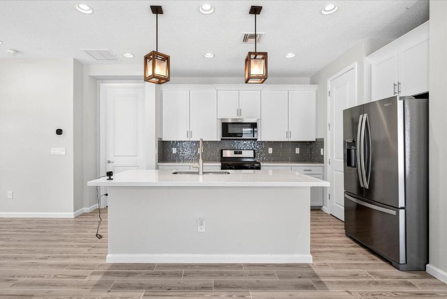 Don't miss the most affordable newer Lilac model home in the highly sought-after gated community of Manderlie at TRADITION! This modern Coastal-style home delivers eye-catching curb appeal and effortless comfort. Enjoy peace of mind with impact-resistant windows and doors, and elevate your cooking experience in the gourmet kitchen featuring stainless steel appliances, a natural gas range, White Sand granite countertops, 42'' upper cabinets, and upgraded plank tile flooring. The open-concept layout shines with soaring 9'4'' ceilings and an elegant tray ceiling in the Great Room, filling the space with natural light. Start your mornings on the charming front porch or relax on the covered lanai. Packed with upgrades and designed to impress—this standout home is a must-see!