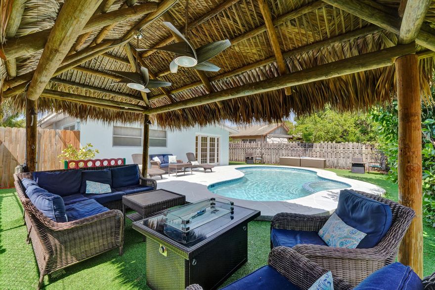 Fantastic East Pompano pool home.  This 3/2 has great square footage (1761)  The house has  incredible layout and flow. Huge kitchen with tons of counter space opens up to the wide open living spaces. Massive windows along the side of the house pull in awesome natural lighting. This backyard oasis is a tropical paradise.  Newly remodeled pool with low maintenance turf and an incredible tiki hut that is begging you to CHILL.  The fenced yard creates a perfect private setting. One car garage, spacious driveway, and charming curb appeal complete the package. A wonderful opportunity to enjoy the Florida lifestyle every day. The home has been professionally painted inside and out.  Roof is only 8 years old.  AC is 2025 — Walk to the Pompano Amphitheater / Pompano Park.