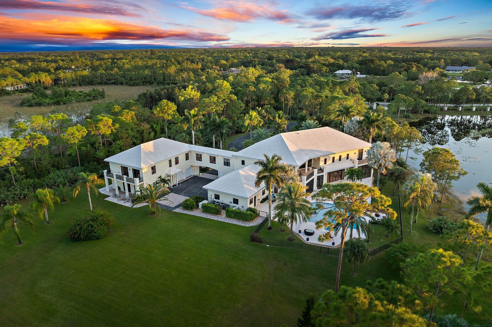 **JUPITER'S PREMIER RANCH ESTATE** Sited on 7.6 Acres of verdant grounds, this grand residence has been meticulously + thoroughly RENOVATED to PERFECTION. A manned guard house welcomes you to RANCH COLONY, a private enclave offering Equestrian trails and 2 nearby Championship golf courses. An Owner's gate +350' driveway lead to the stately 11,402 sq. ft home. A grand entry foyer w/ 28' ceiling is graced by brilliant marble floors and a dramatic double staircase of Brazilian wood. Classic design elements incorporate timeless elegance + modern luxury. The interiors have been finely curated for an elevated living experience, offering a spacious + harmonious floor plan and abundant natural light. The main living areas are grand in size and epitomize tasteful elegance. The huge open