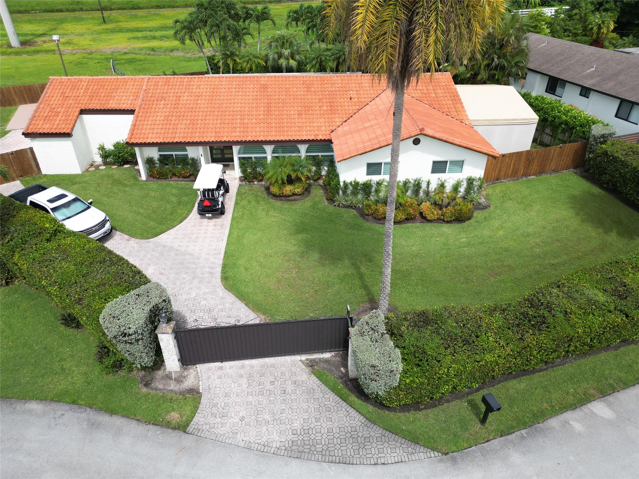 Fully remodeled 4BR/2.5BA tropical paradise gated home on cul-de-sac! Towering palms and vibrant greenery create a private retreat, while the oversized driveway offers plenty of space for guests. Features impact windows, a 2-car garage, RV/boat parking & a 300 sq. ft. bonus room on side of home perfect for office, gym/studio. Light-filled open layout with custom cabinets and lighted quartzite in kitchen and a spacious living area. Primary suite offers a large modern en-suite. Backyard is a private resort with pool, basketball court, lush landscaping, avocado & tangerine trees. Backs to 20 acres of FPL land—no rear neighbors! Garage has A/C for perfect man-cave. Tropical landscaping creates a serene retreat, perfect for relaxing year-round in the ultimate Florida lifestyle!