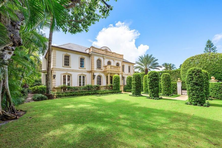 This extraordinary estate at 242 Wells Road combines classic French Provincial architecture with timeless elegance, offering an unparalleled lifestyle on one of Palm Beach's most prestigious streets. This magnificent 7,460 total sq. ft. French Provincial masterpiece is nestled on a sprawling 19,500 sq. ft. lot in the heart of Palm Beach. This stately manor, with its steep-pitched slate roof, symmetrical façade, and stone surrounds, exudes Old World charm and impeccable craftsmanship. The home's architectural grandeur is enhanced by graceful balustrades and meticulously sculptured landscaping, creating a serene and sophisticated retreat. Step inside to find luxurious interiors adorned with gleaming hardwood and marble floors showcasing exceptional attention to detail. A grand staircase, a stunning centerpiece of the foyer, welcomes you with its sweeping elegance, complemented by a private elevator. The residence offers 4 spacious bedrooms, 6 beautifully appointed bathrooms, and one half bath, fully furnished for effortless move-in elegance. The crown jewel is the expansive primary suite, featuring an expansive balcony overlooking the breathtaking pool and lush, professionally curated gardens. This serene retreat includes his-and-hers walk-in closets, separate opulent bathrooms with high-end finishes, and an elegant sitting room, perfect for quiet relaxation or intimate gatherings. A generously appointed guest suite also boasts its own balcony, offering stunning views of the tranquil outdoor oasis. Entertain with unparalleled style in the formal dining room, ideal for grand gatherings, seamlessly connected to a large butler's pantry and wet bar equipped for effortless hosting. The eat-in kitchen, a chef's dream, blends modern functionality with classic design, featuring top-tier appliances and ample space for casual dining. A stately fireplace anchors the formal living room, while a refined library provides an ideal space for work or leisure. Step outside to the large wraparound loggia or the luxurious balconies off the primary and guest suites, all offering captivating views of the expansive pool and gardens.  The estate is complete with a 3-car garage with ample storage.