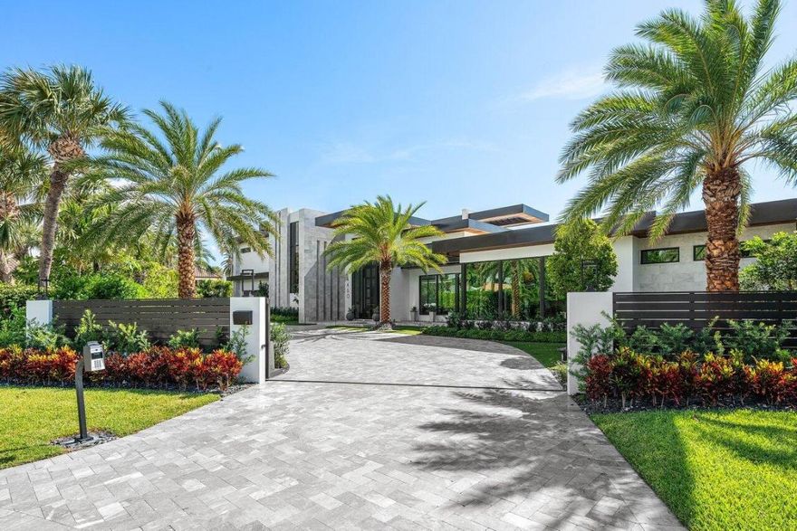 A Masterpiece of Modern Waterfront Living. Introducing a newly constructed, gated contemporary estate that redefines luxury on the Intracoastal Waterway, perfectly positioned on an expansive 161± feet of prime no-wake frontage directly across from the prestigious estates of Hillsboro Mile. Designed as a one-of-a-kind architectural statement, this glass-encased residence offers uninterrupted front-row views from nearly every major room, creating a seamless connection between interior elegance and the surrounding waterfront beauty. An awe-inspiring arrival begins with a cascading water wall entry that sets the tone for the exceptional design that follows. Inside, ultra-refined finishes abound—from a bespoke chef's kitchen with professional-grade appliances to imported tile, custom lighting, and a sophisticated private elevator. The entire north wing of the upper level is dedicated to an opulent Primary Suite sanctuary, featuring dual spa-inspired bathrooms, a private executive office, boutique-style wardrobe rooms, and an expansive sky deck offering panoramic views of the Intracoastala true personal retreat. Designed for both grand entertaining and relaxed resort living, the outdoor space features a sleek pool and spa, entertainment-ready lanai, and meticulously landscaped surroundings. Boating enthusiasts will appreciate the rare state-of-the-art, industrial-grade boat lift, engineered to accommodate significant watercraft, along with deepwater dockage.