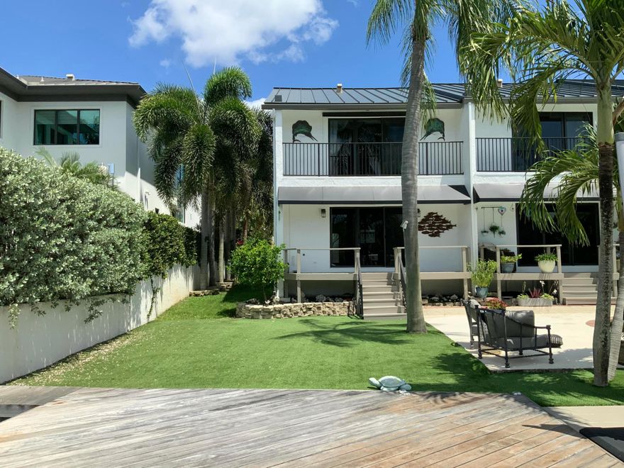 Spectacular Intracoastal townhome — ideally situated on the END of only four residences in this exclusive waterfront community. This 2BD|2.5BA home features unobstructed views of the Intracoastal waterway and protected Deerfield Island Park ensuring a natural backdrop that will remain unchanged and private. This waterfront townhome is complete with private dock built with concrete pilings, Brazilian hardwood decking, a raised seawall, rip rap protection and an 8,000 lb lift with water and electric dockside. Located in a no-wake zone with quick access to both Boca and Hillsboro Inlets. Designed with rich mahogany upstairs floors and stairs, warm cypress plank ceilings on the 2nd floor and half bath. Primary bedroom includes remote-controlled shades and a spa-inspired bath with a carved wood travertine vessel sink, clawfoot soaking tub, and frameless natural-stone walk-in shower with upgraded 3/4" supply lines. Second bath features a custom wood pedestal vanity with carved wood vessel sink and walk-in shower. Second bedroom is used as a flexible office with custom built-in shelving. A summer kitchen extends entertaining outdoors, with well-maintained grounds and a community pool set directly on the Intracoastal just steps away. Home includes a generator, all impact windows, new metal roof and hurricane-rated garage door. Parking for two cars, including garage. Great location with easy walk to beach, Deerfield Beach Pier, oceanfront restaurants and shops.