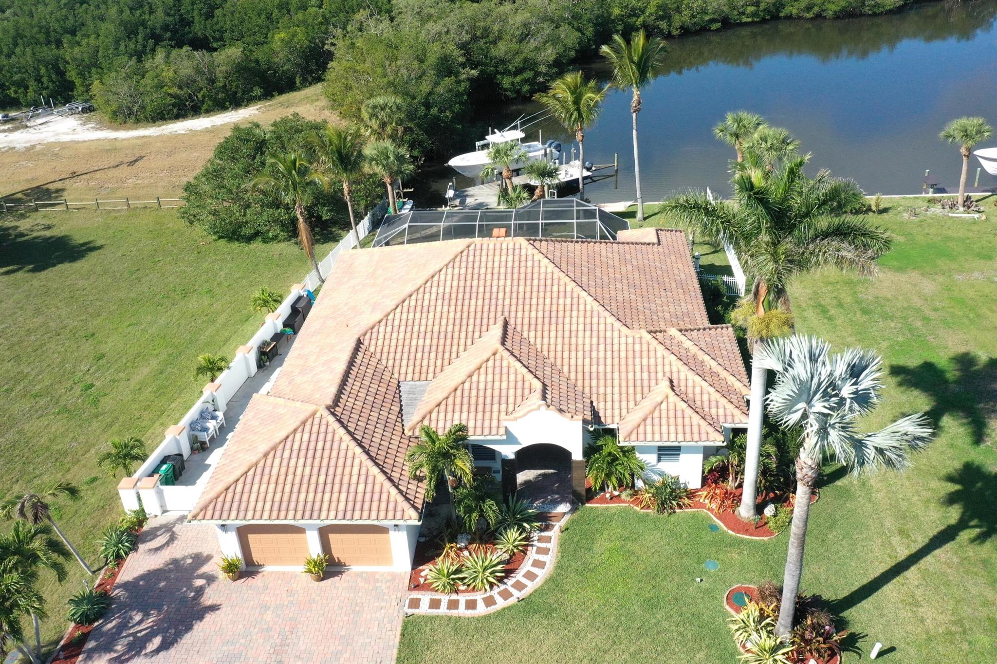 ADDITIONAL ACREAGE NOW OFFERED SEPARATELY! Stunning renovations completed in '24 will amaze in this luxurious 4 Bed/3.5 Bath custom waterfront smarthome w 2.5 car garage, screened pool & angled dock w two boat lifts, addt'l floating dock & 50A shore power! Countless features will impress incl the gorgeous kitchen w double island, wet bar, den & separate 'zen' room, impact windows & doors, custom accents & built ins, this home is truly a MUST SEE!! Just 1/4 mile walk to private beach access! 1.96 acre surrounding waterfront property w addt'l homesite & mangrove nature trail also available!