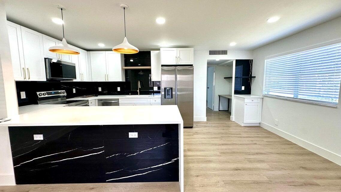 Stunning ground-floor unit with garden views! Over $50,000 in upgrades, all fully permitted, and the unit has undergone a complete renovation. It features luxury waterproof vinyl plank flooring, brand new Samsung appliances, quartz countertops with a waterfall edge, and new white shaker cabinets with a garbage pull-out. There's also a corner coffee bar and a custom office nook with LED lighting. The master bathroom boasts a walk-in tiled shower with a glass panel, and modern cabinets with LED-lit mirrors in both bathrooms. Keyless entry, updated ceilings with LED lights, new 2024 AC unit, washer/dryer, and electrical panel upgrade. The building is also freshly painted. Resort-style amenities include pools, clubhouses, golf, tennis, and more. Minutes from beaches, dining, and shopping!